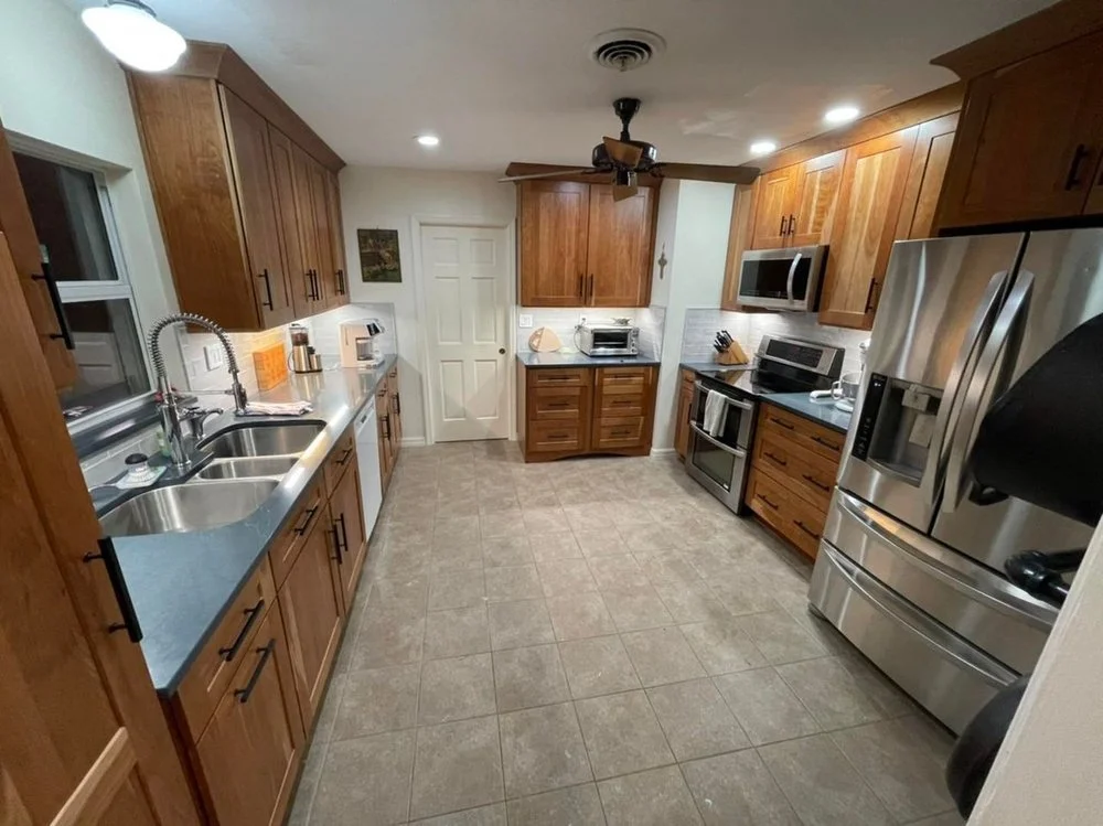 Modern kitchen with wooden cabinets, stainless steel appliances, double sink, and ceramic tile flooring.