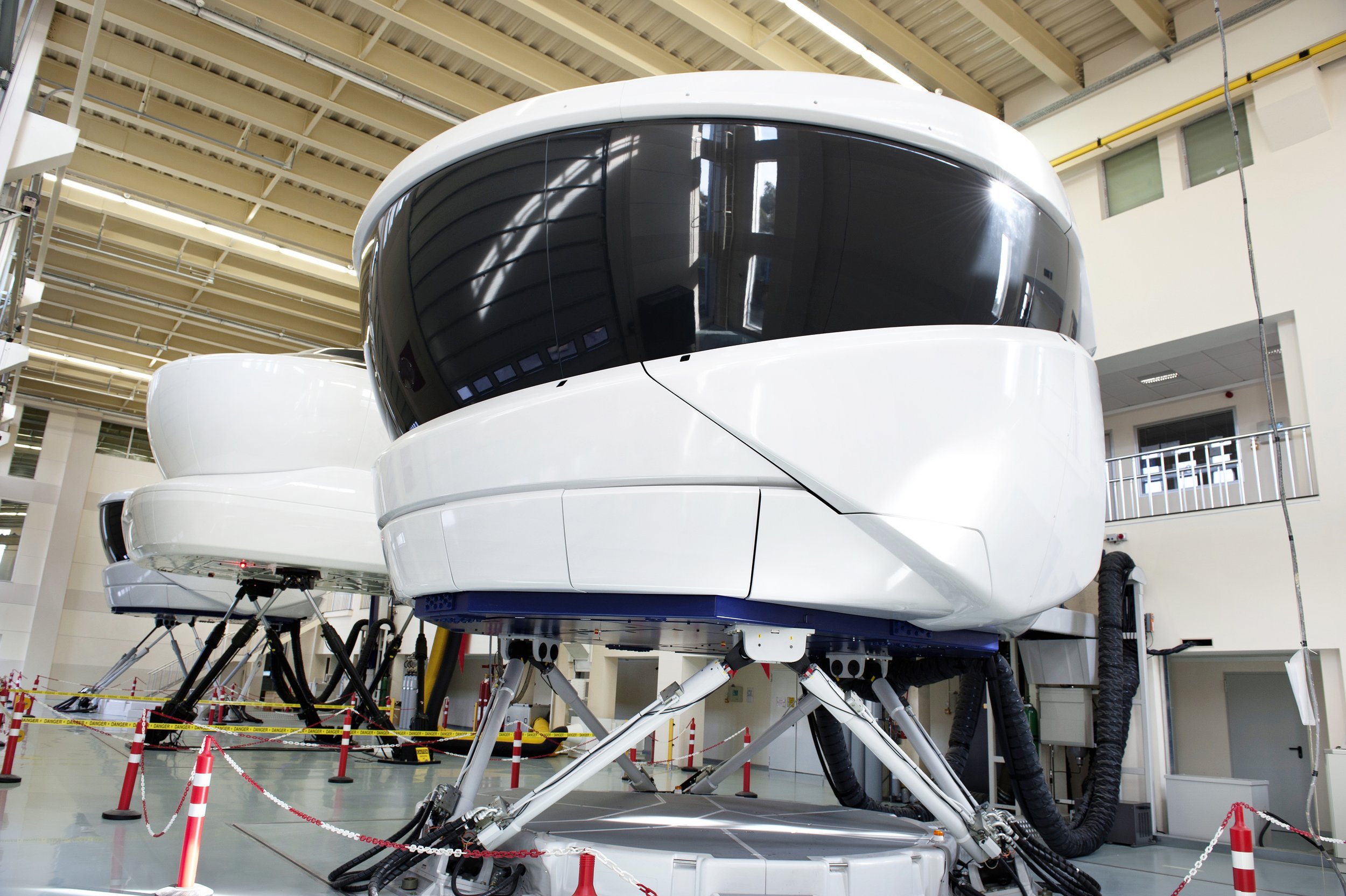 Flight simulator in a training facility with hydraulic legs and a cockpit structure.