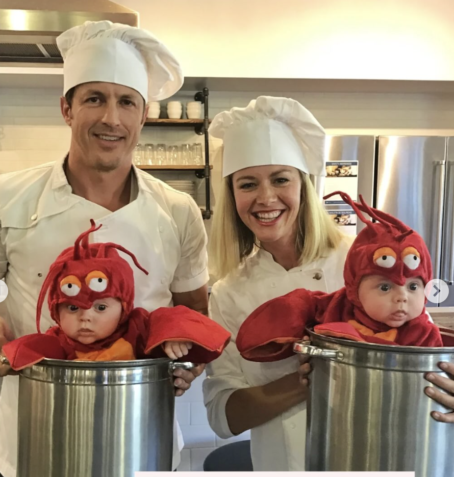 Kristin and Jeremy dressed as chefs holding two large pots with the twin boys dressed as lobsters