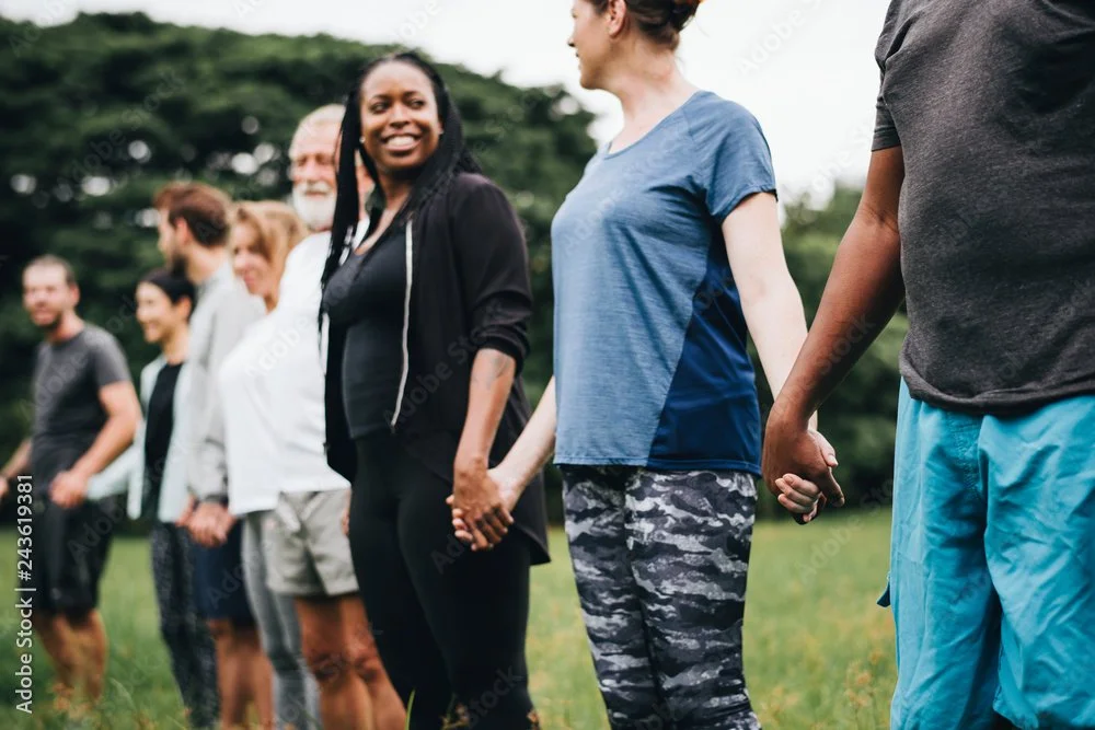 Group of diverse people standing outdoors, holding hands in a line