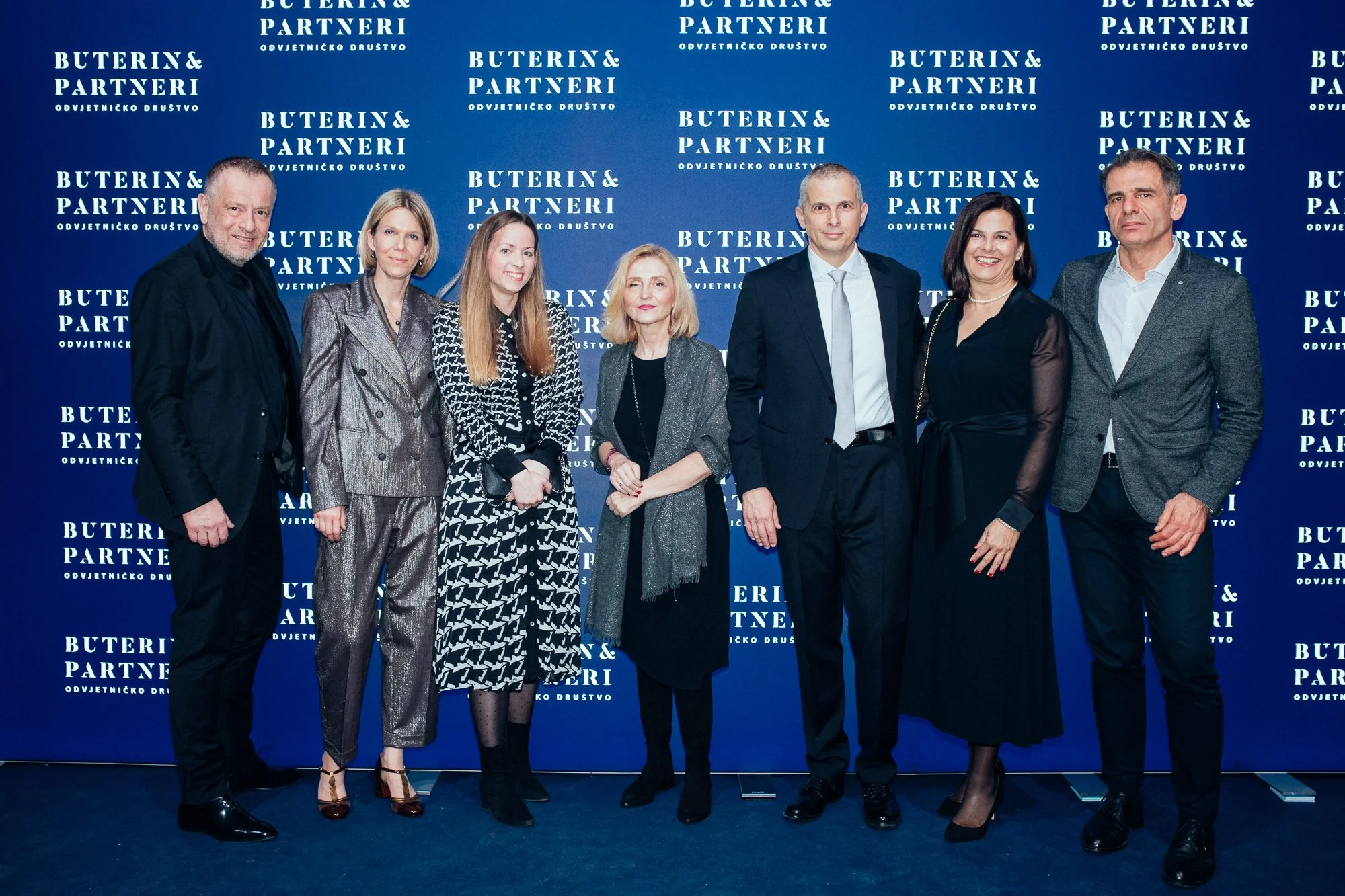 Group of seven people standing in front of a blue backdrop with white text that reads 'Buterin & Partneri Odvjetničko Društvo'.
