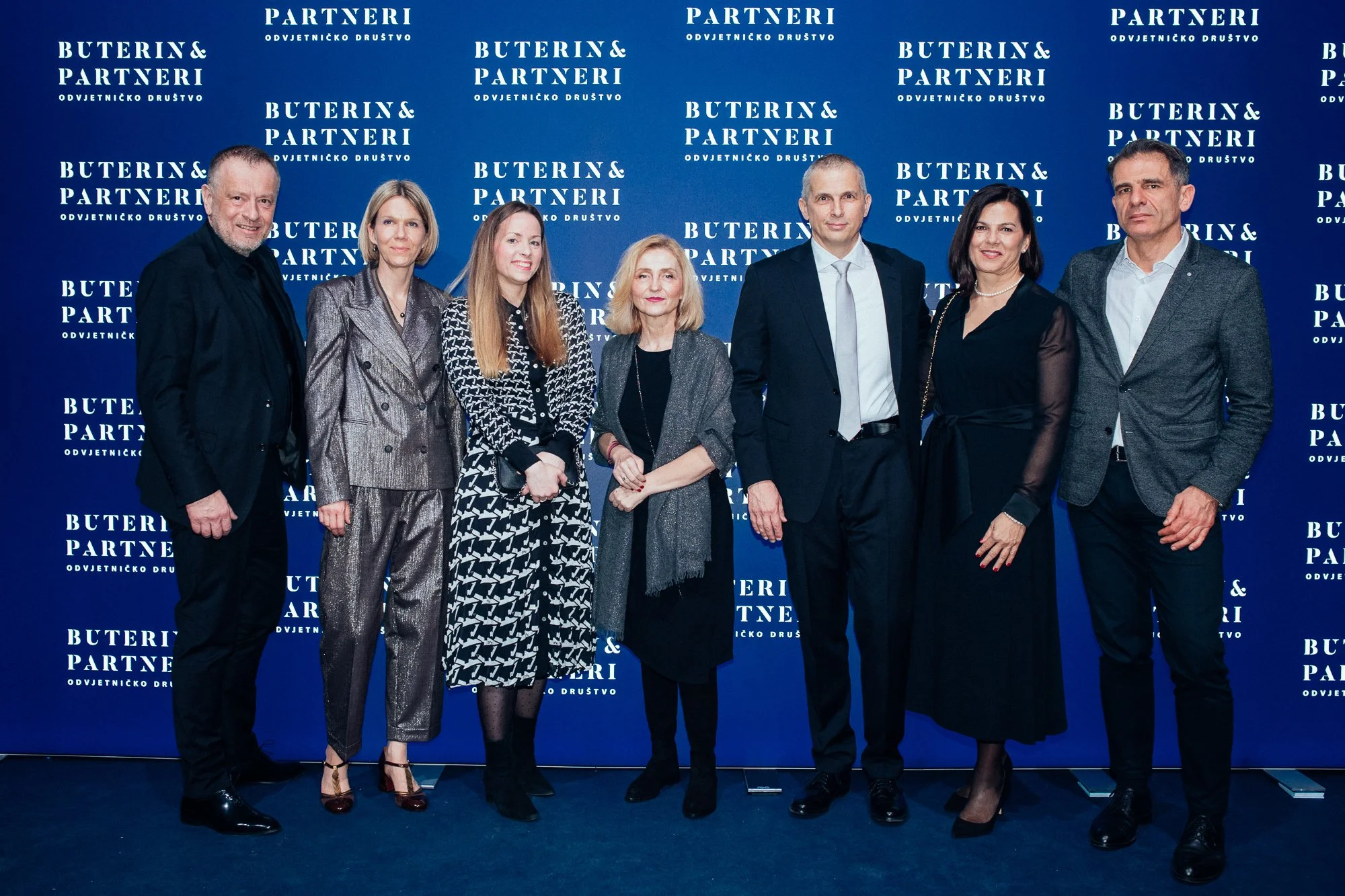 Group of eight professionally dressed people standing in front of a blue backdrop with white text that reads 'Buterin & Partneri' and 'Odvjetničko Društvo'.