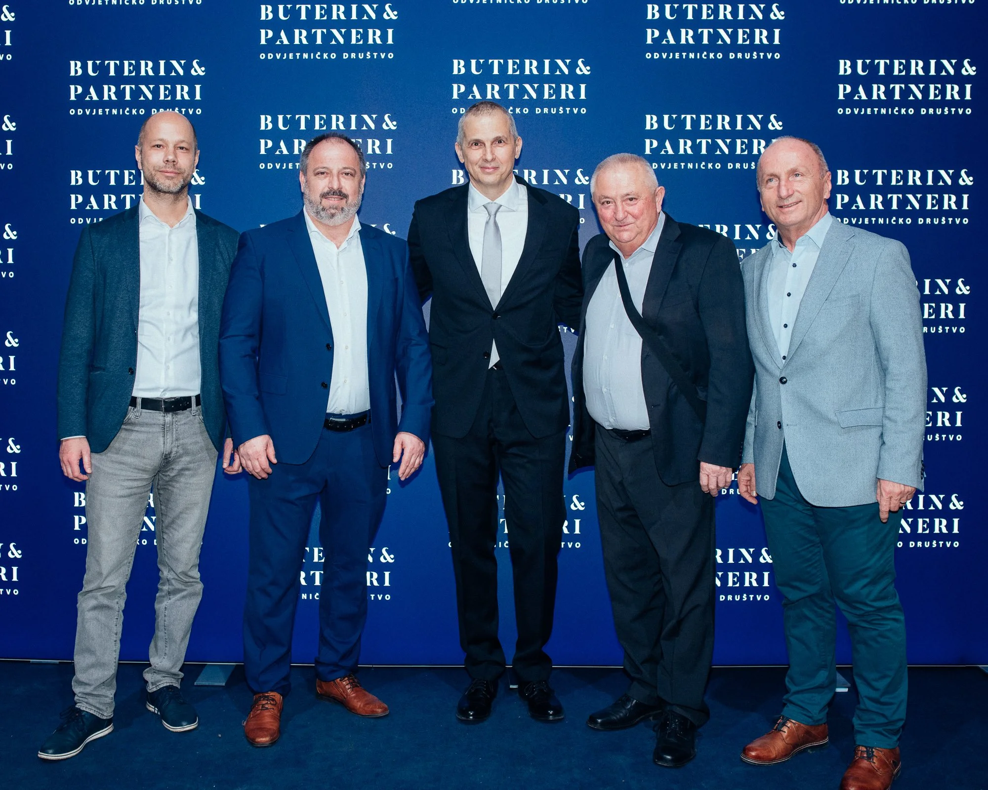 Six men in suits standing in front of a blue backdrop with white text that reads 'Buterin & Partneri.'