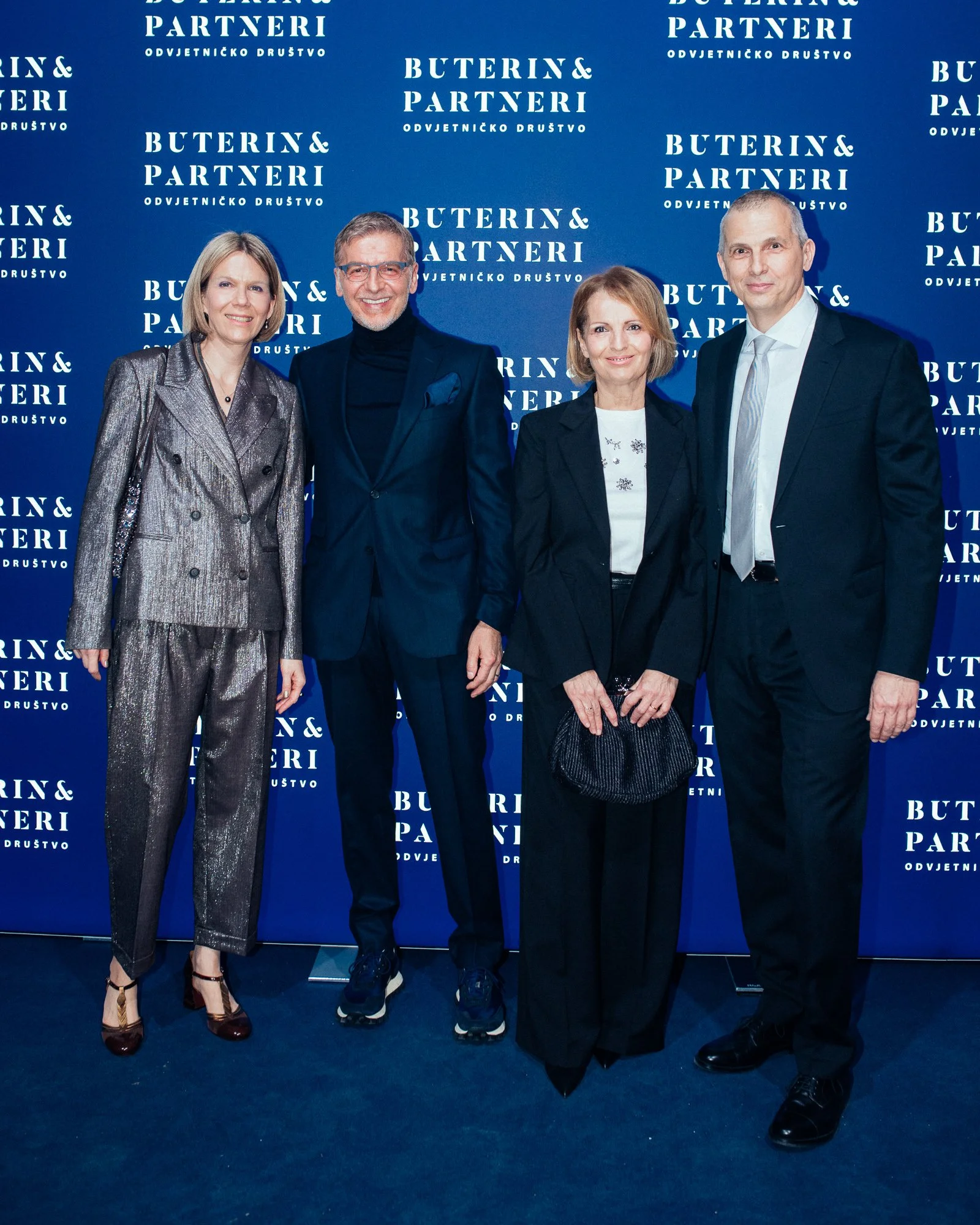Four people standing in front of a blue backdrop with white text that says "Buterin & Partneri Odvjetničko Društvo." The group includes two women and two men, all dressed in formal attire, smiling for the camera.