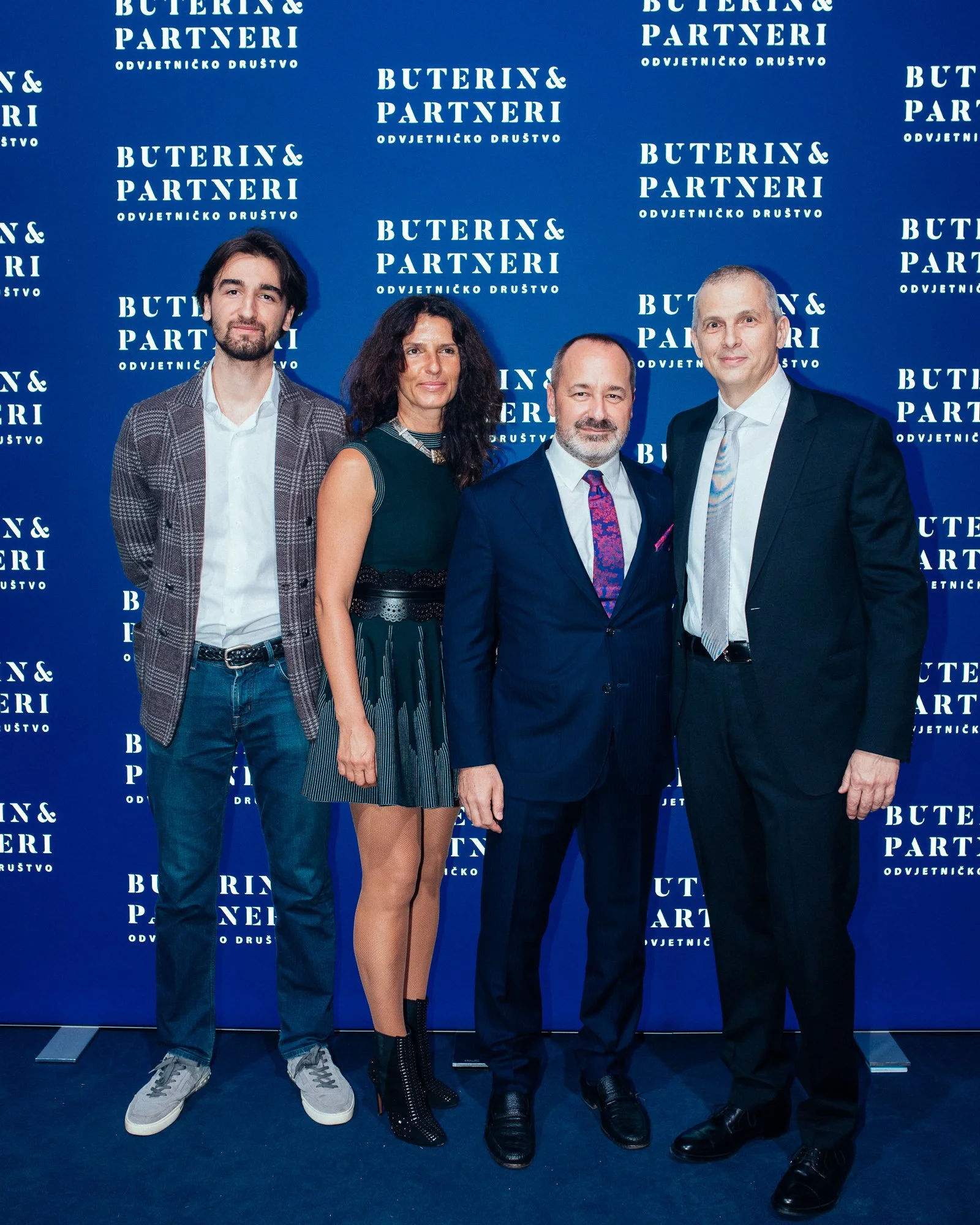 Four people standing in front of a blue backdrop with white text that reads 'Buterin & Partneri Odvetnicko Drustvo'. They are dressed in formal attire, posing for a group photo.