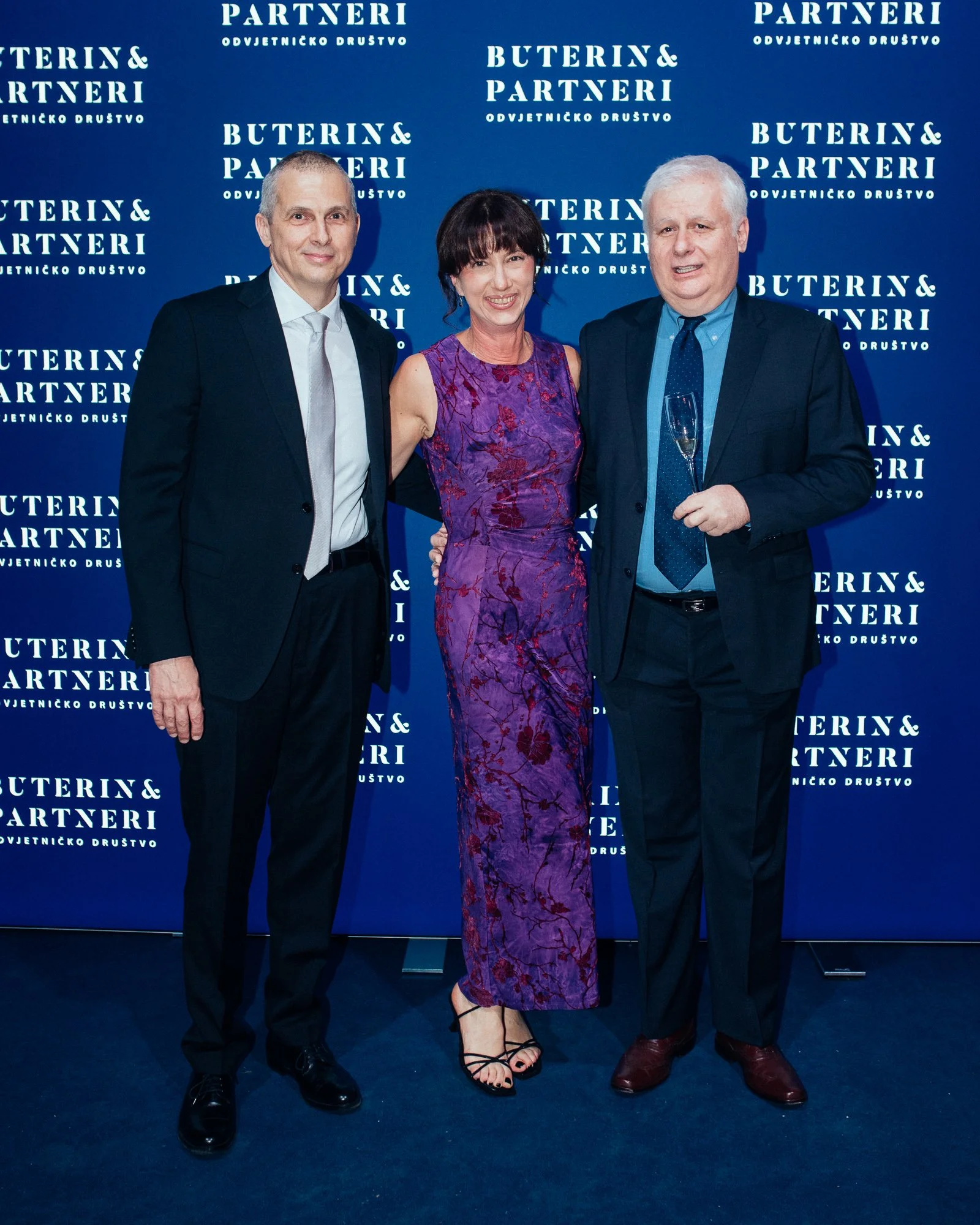 Three people dressed in formal attire posing in front of a blue backdrop with the text 'Buterin & Partneri Odvjetničko Društvo.'