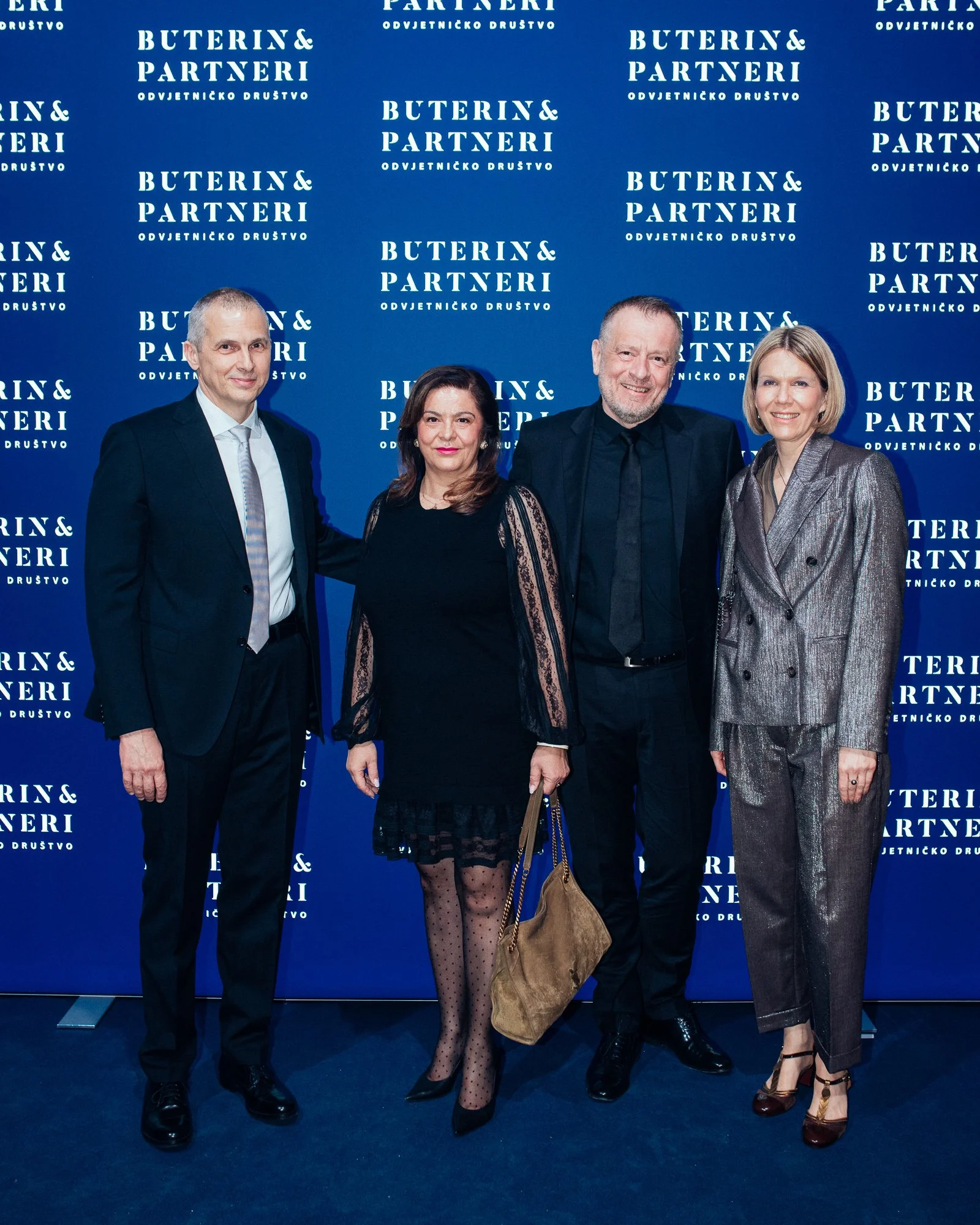Four people dressed in formal attire standing in front of a blue backdrop with the text 'Buterin & Partneri Odvjetnicko Drustvo'.