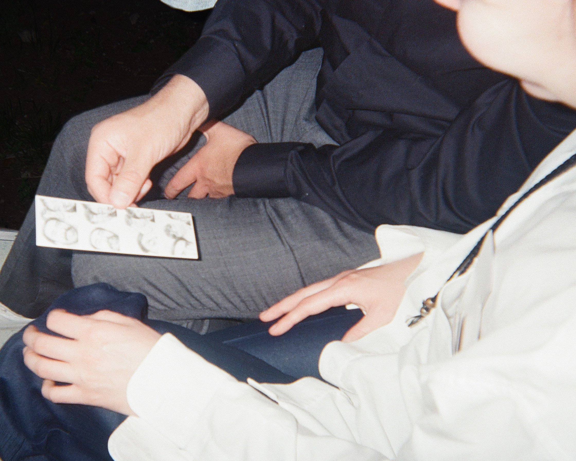 Two people sitting together, one showing a strip of photo booth images to the other. Both are dressed formally, and they are seated in an wedding setting.