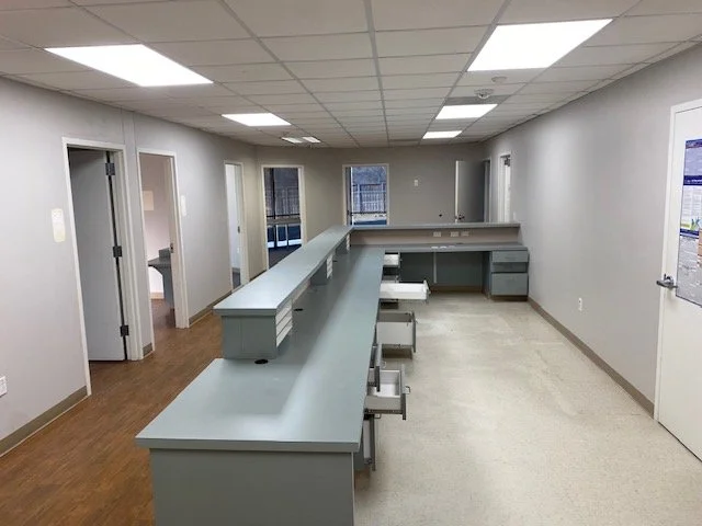 Empty medical reception or nurse station with gray counters and stools in a clinic or hospital interior.