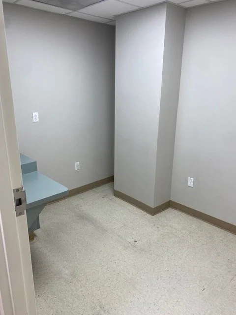 Empty room with gray walls, a small built-in desk, and electrical outlets.
