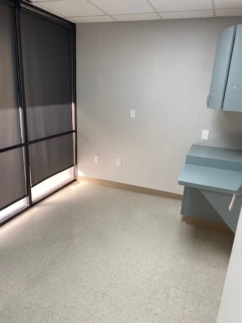 Empty room with a large window, light-colored walls, and a blue countertop in the corner.