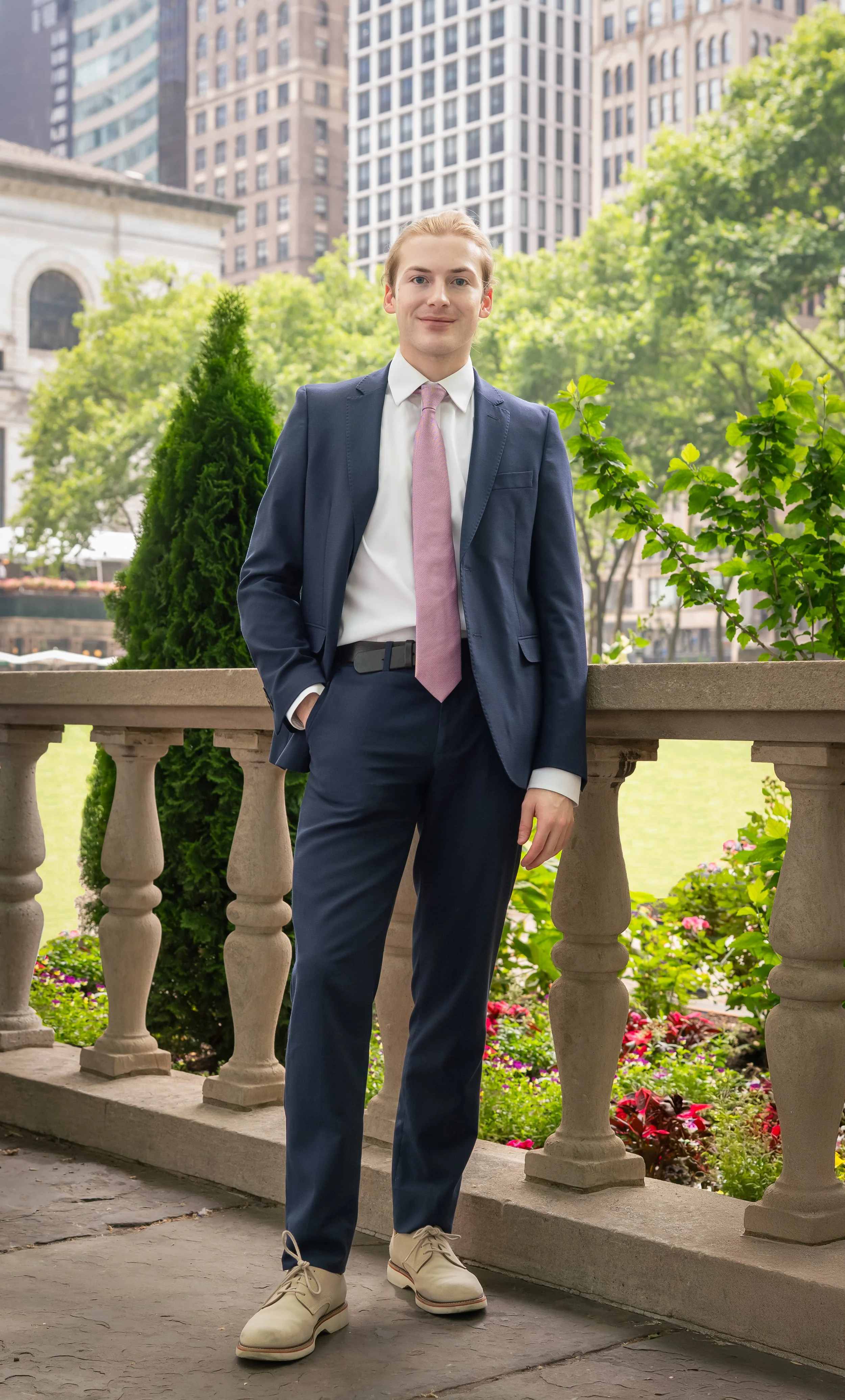 Professional outdoor headshot of a young man in a navy suit in New York City