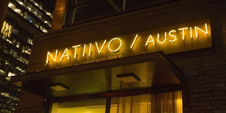 Illuminated sign reading 'NATIVO / AUSTIN' on a brick building at night.