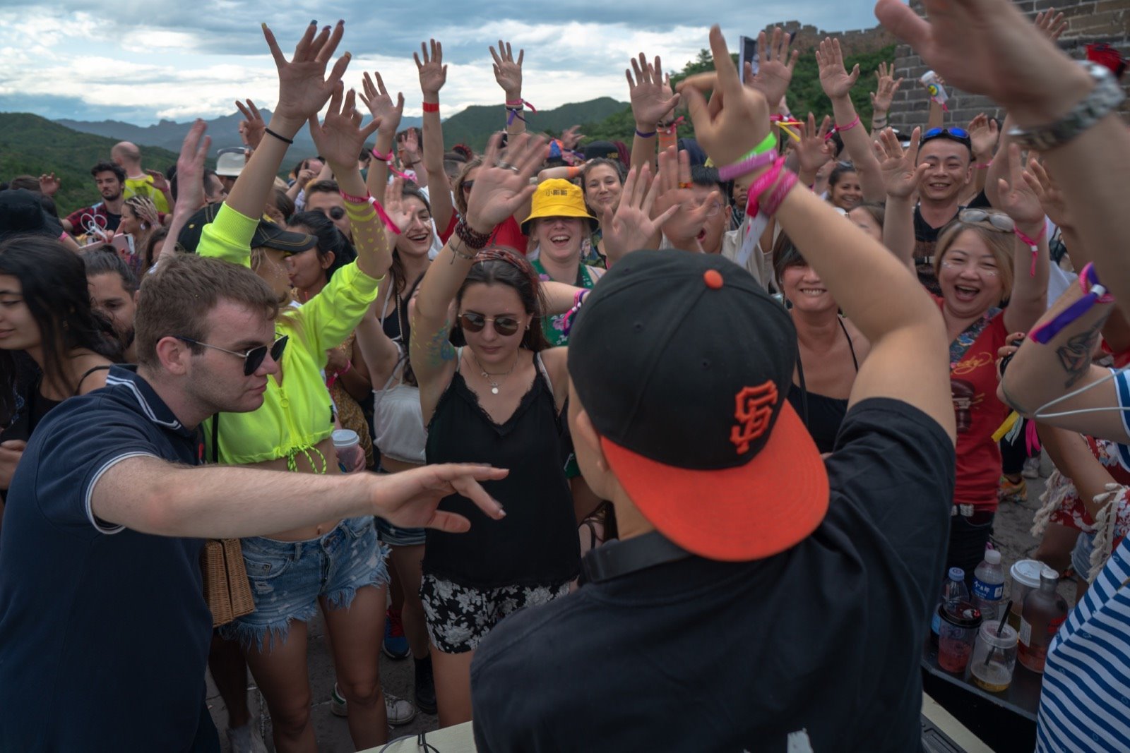Crowd of people dancing and cheering at an outdoor music event.
