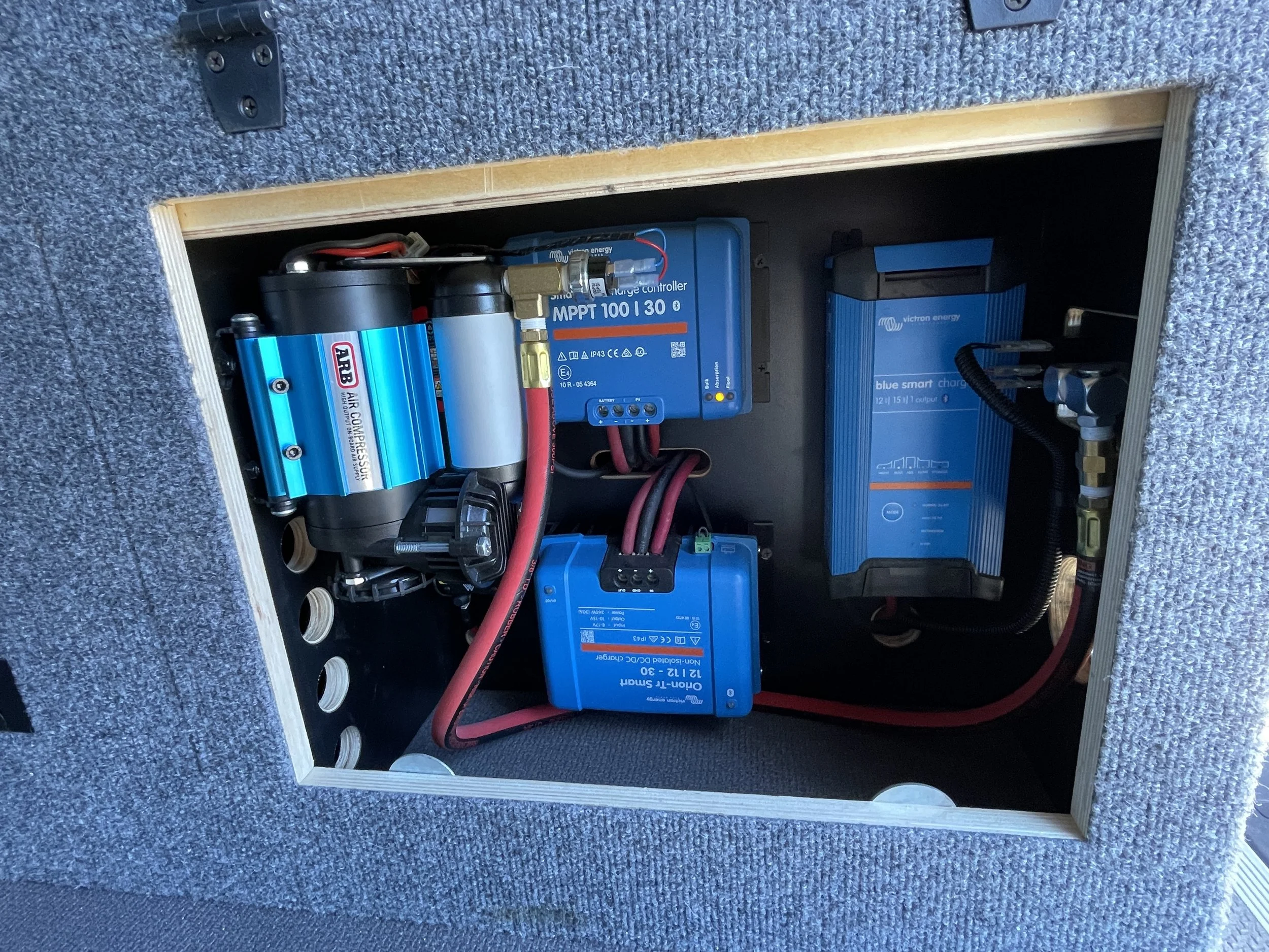 Inside of a vehicle compartment showing electronic components including a compressor, MPPT controller, and smart charger.