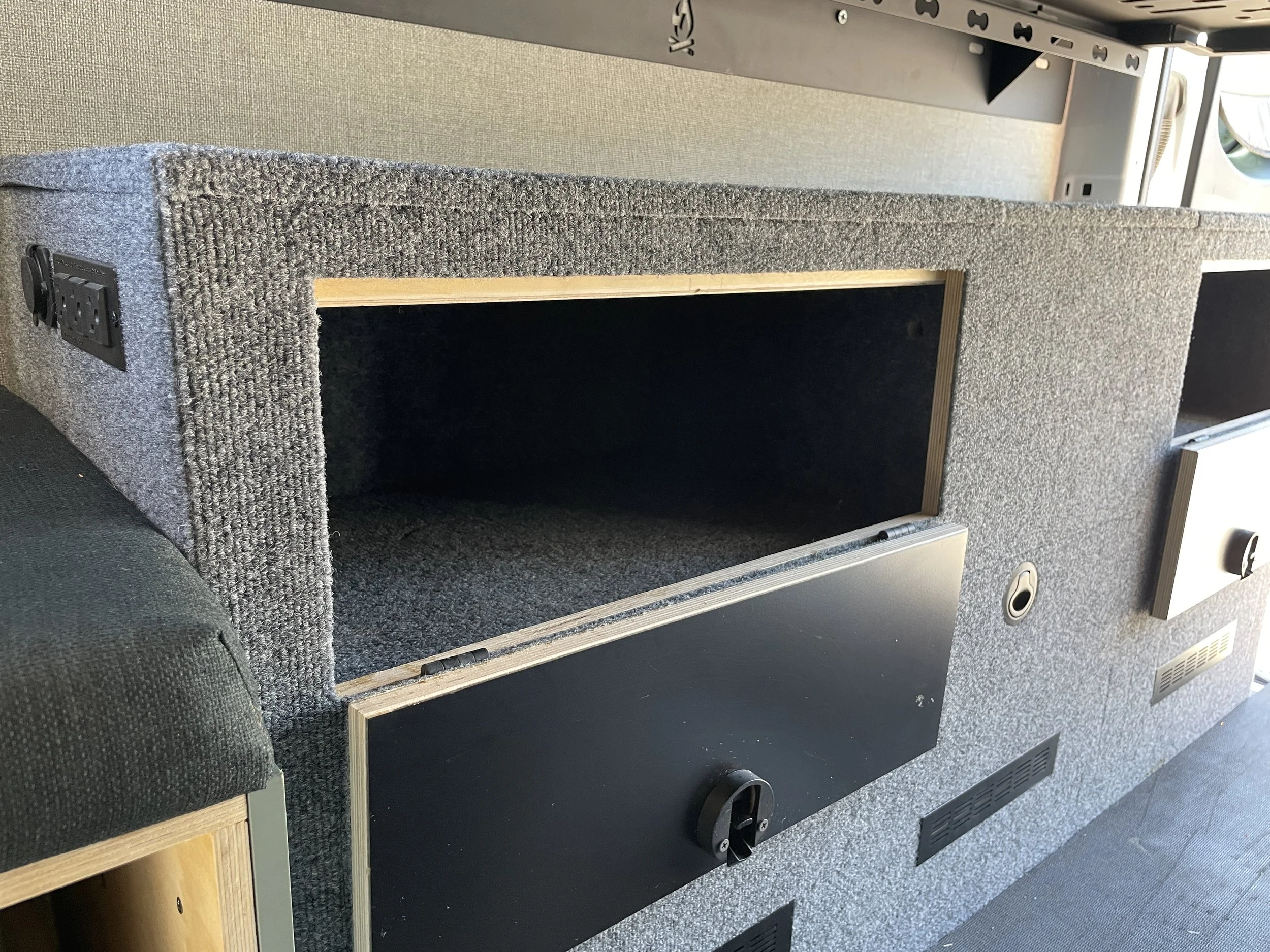 Interior of a van showing a carpeted storage compartment with open doors.