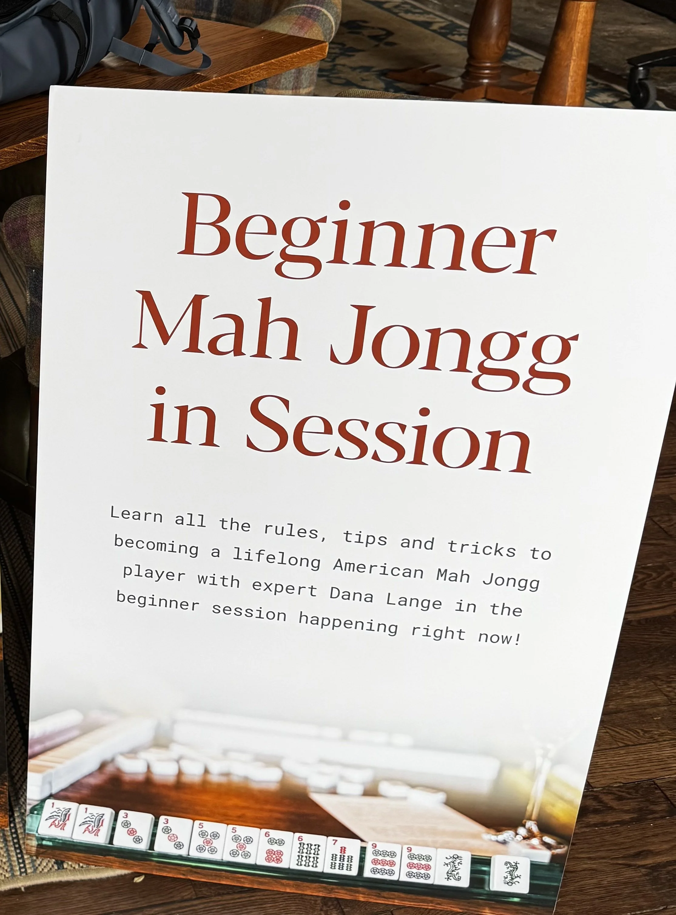 Signboard promoting Dana Lange's beginner Mah Jongg sessions with rules, tips, and tricks, featuring Mah Jongg tiles at the bottom.