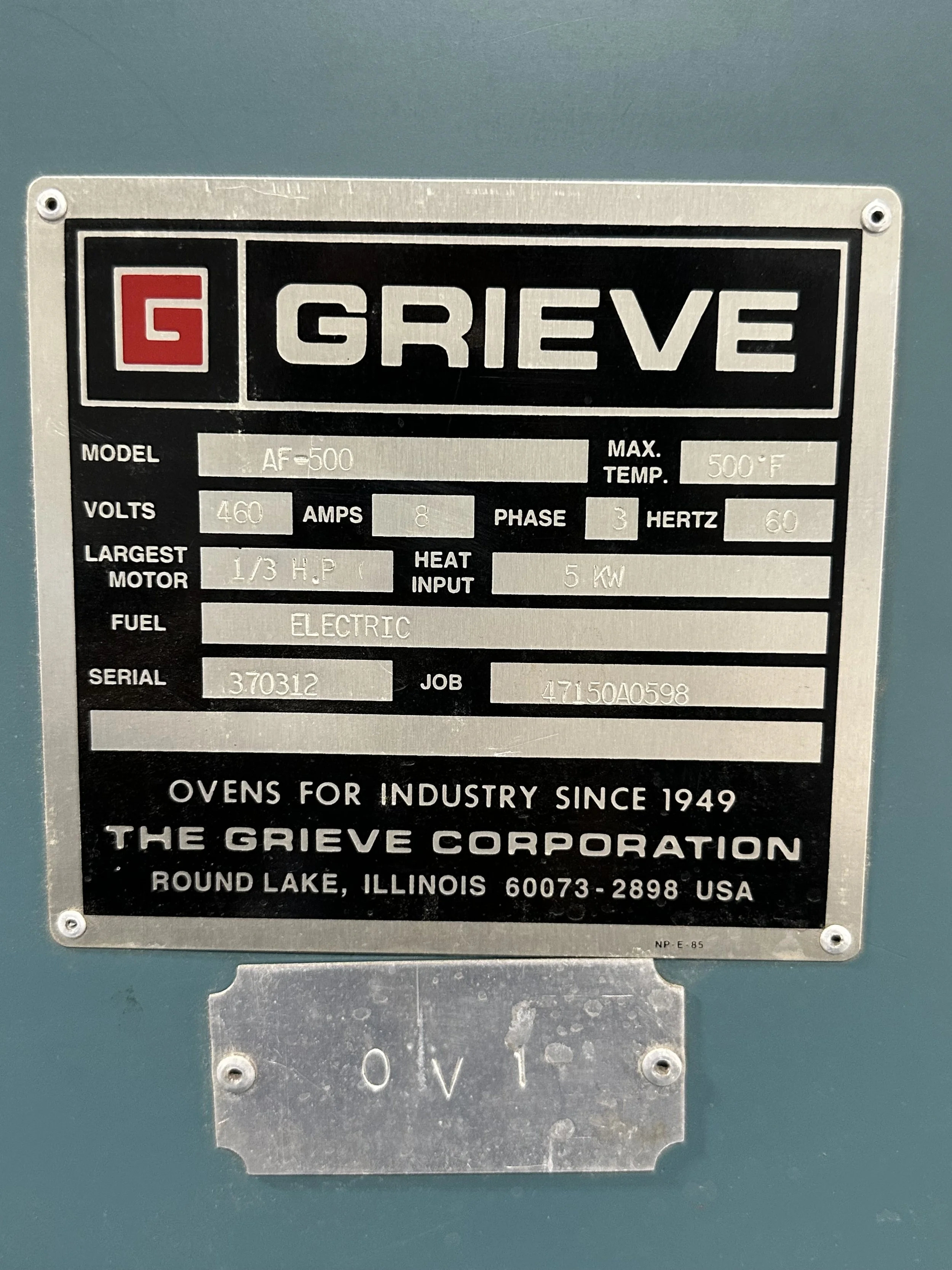 A metal nameplate on industrial equipment indicating model AF-500, voltage 460 volts, current 8 amps, phase 3, frequency 60 hertz, maximum temperature 500°F, largest motor 1/3 horsepower, heat input 5 kW, electric fuel, serial number 3.70312, job number 47150A0598, manufactured by The Grieve Corporation in Round Lake, Illinois.