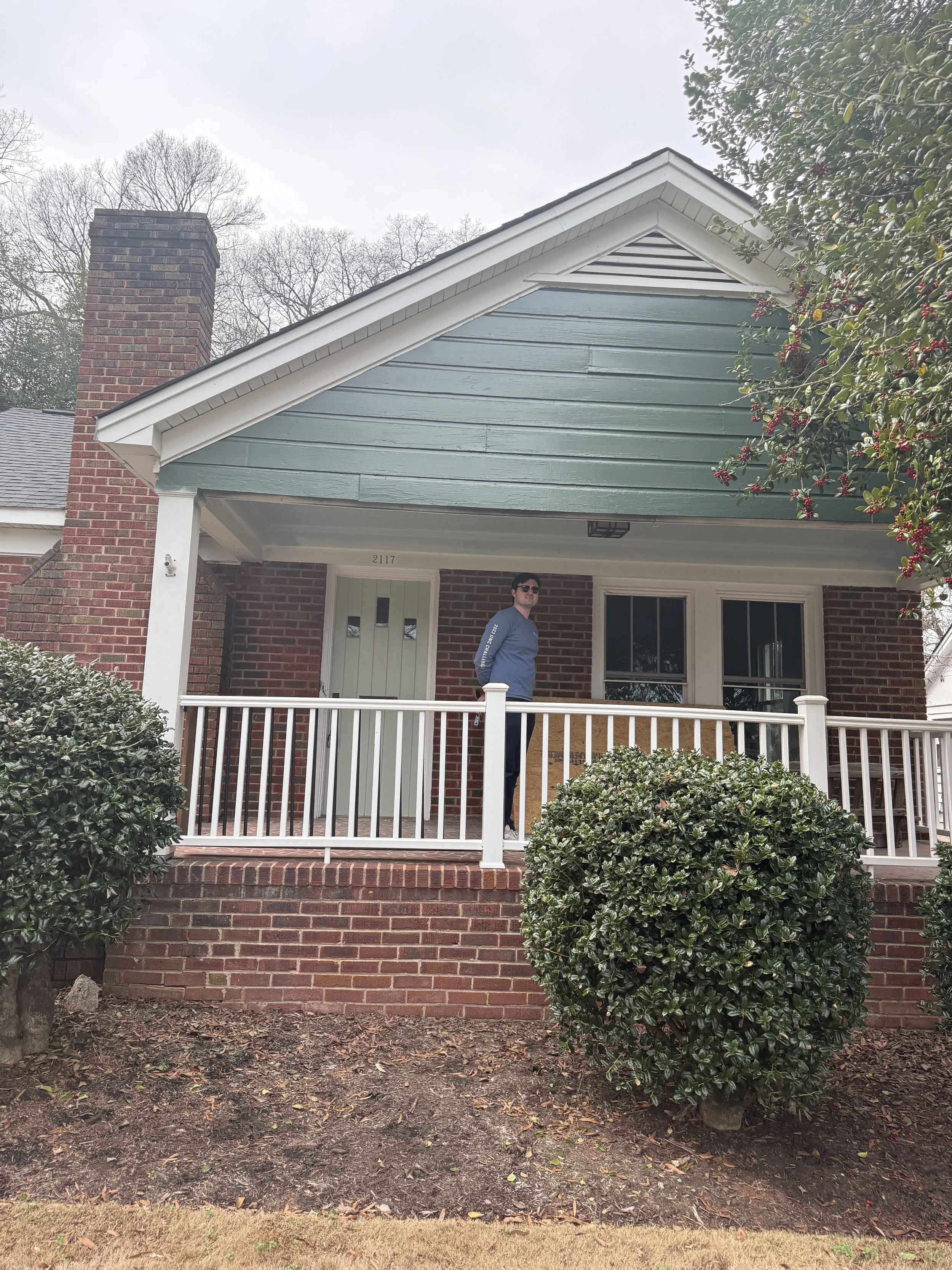 A house is painted a dark green with stray paint marks everywhere and messy application.