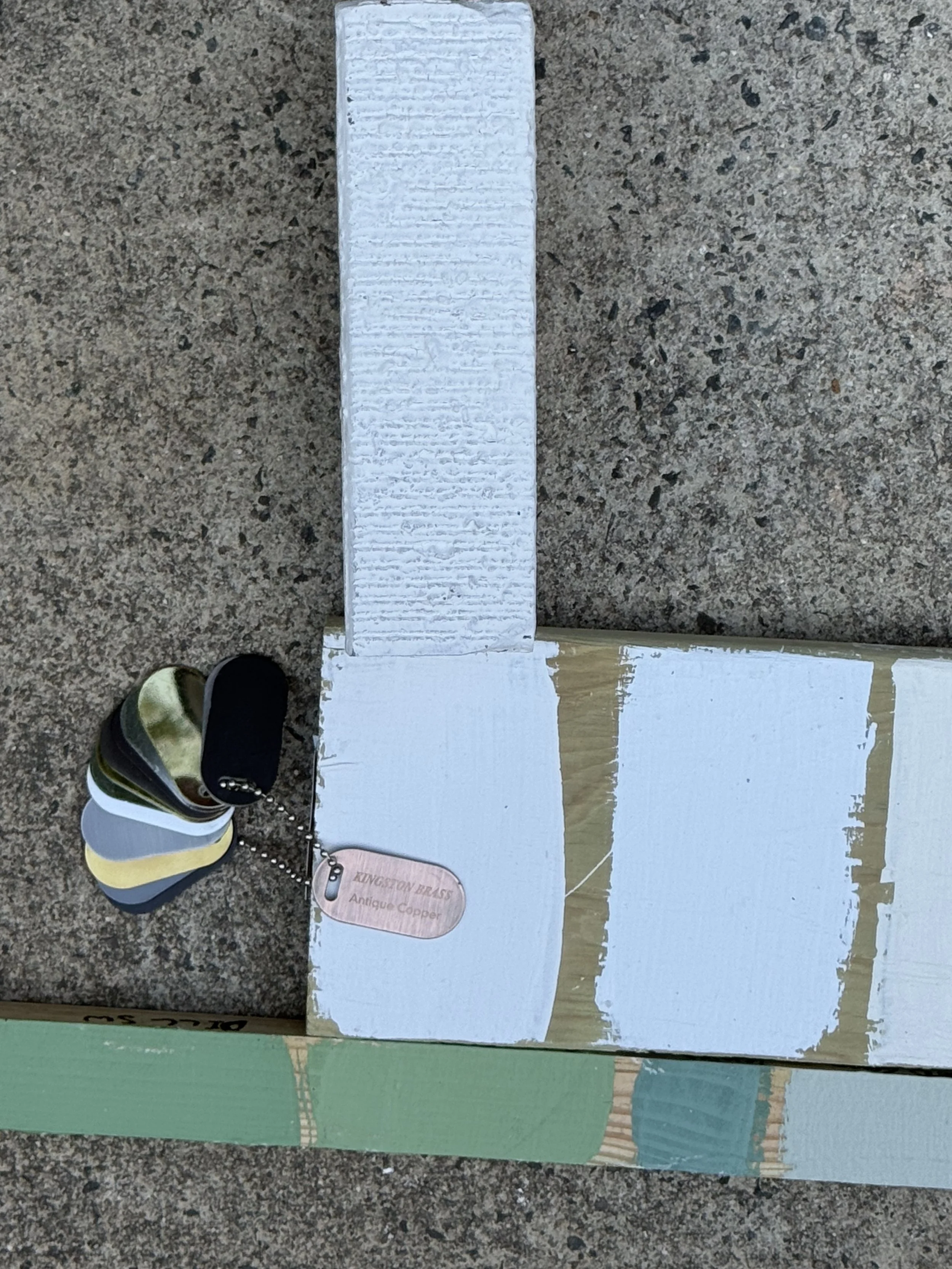 A limewashed brick is shown with a swatch of copper on top of the wood with white paint swatches.