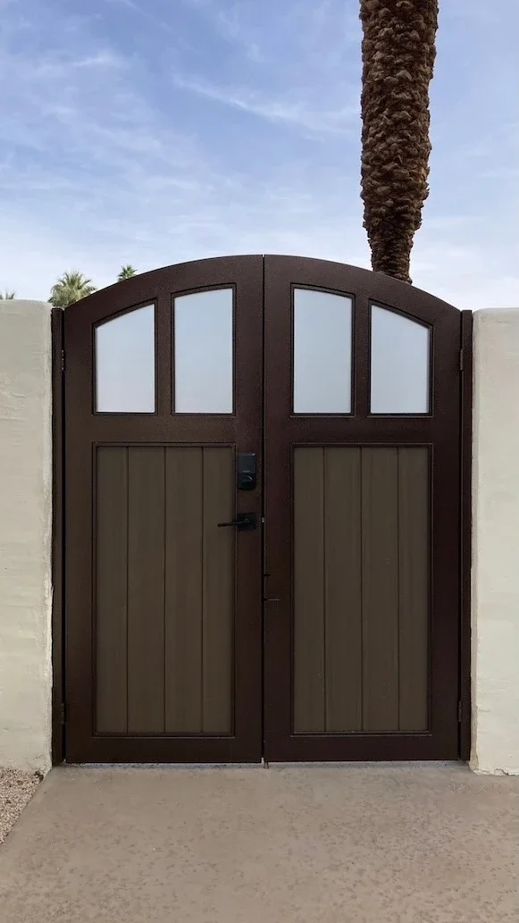 front entry gate with a dark brown steel frame, frosted glass and wood-panel inserts with a black handle and lock