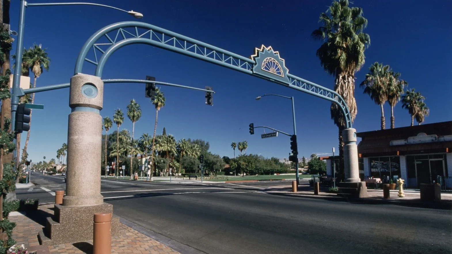 grand green archway with a sunburst at its center beginning on one side of a downtown street and ending on the other with a concrete base