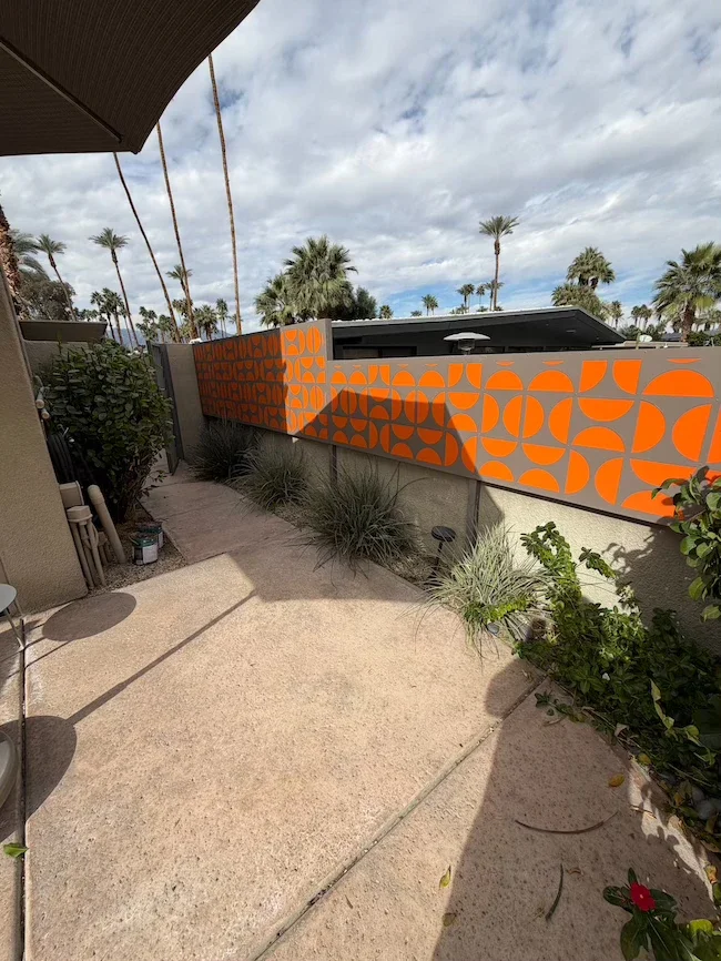 grey privacy panels with orange half-circle designs in a backyard separating this property from the next