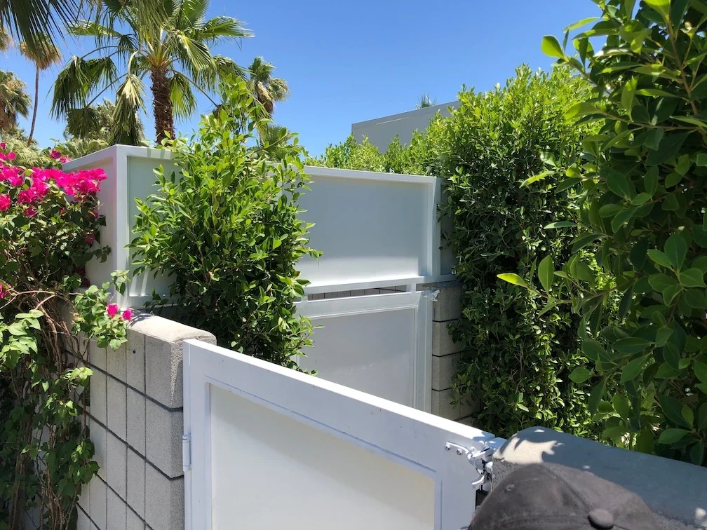 white side yard gate integrated into a block wall with a gate latch that opens to an identical gate and equipment enclosure with matching privacy panels