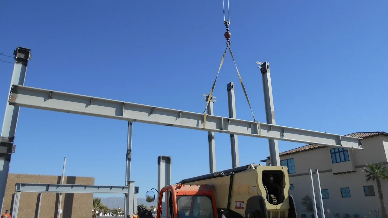 large structural steel beam being installed with a crane on a construction site
