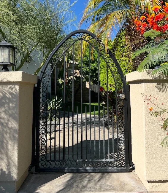black ornamental front gate with a scroll frame, straight bars, and a silver handle