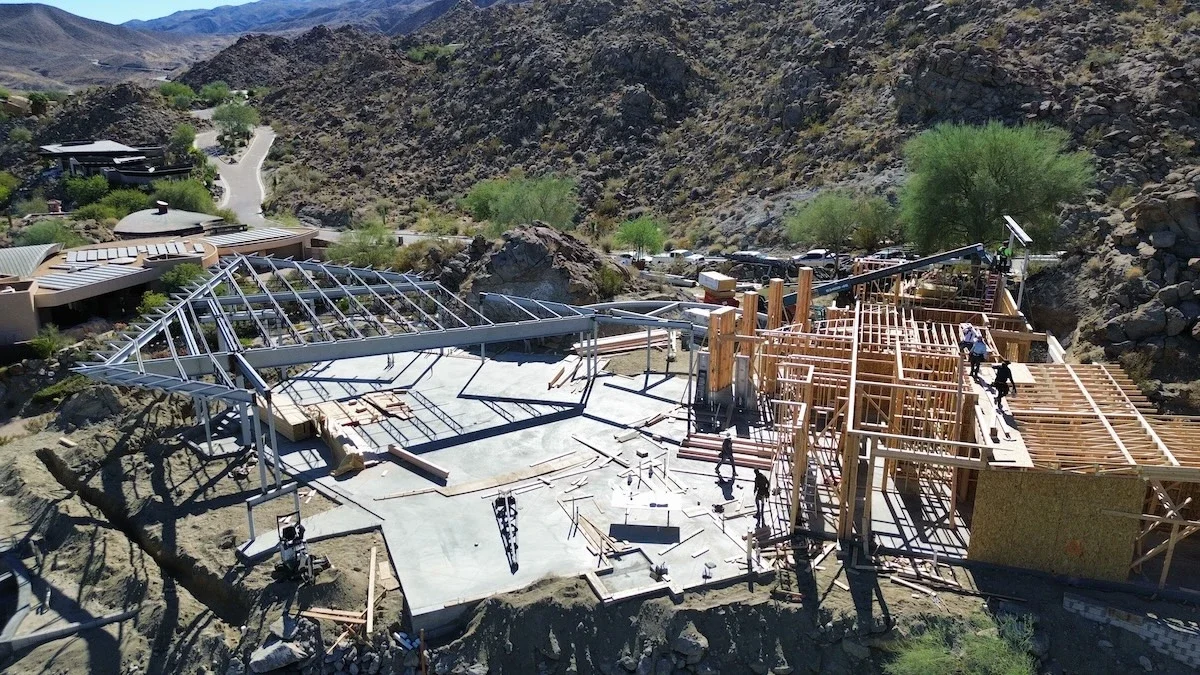 aerial view of the structural steel and wood framing foundations for a luxury home in a neighborhood surrounded by mountains