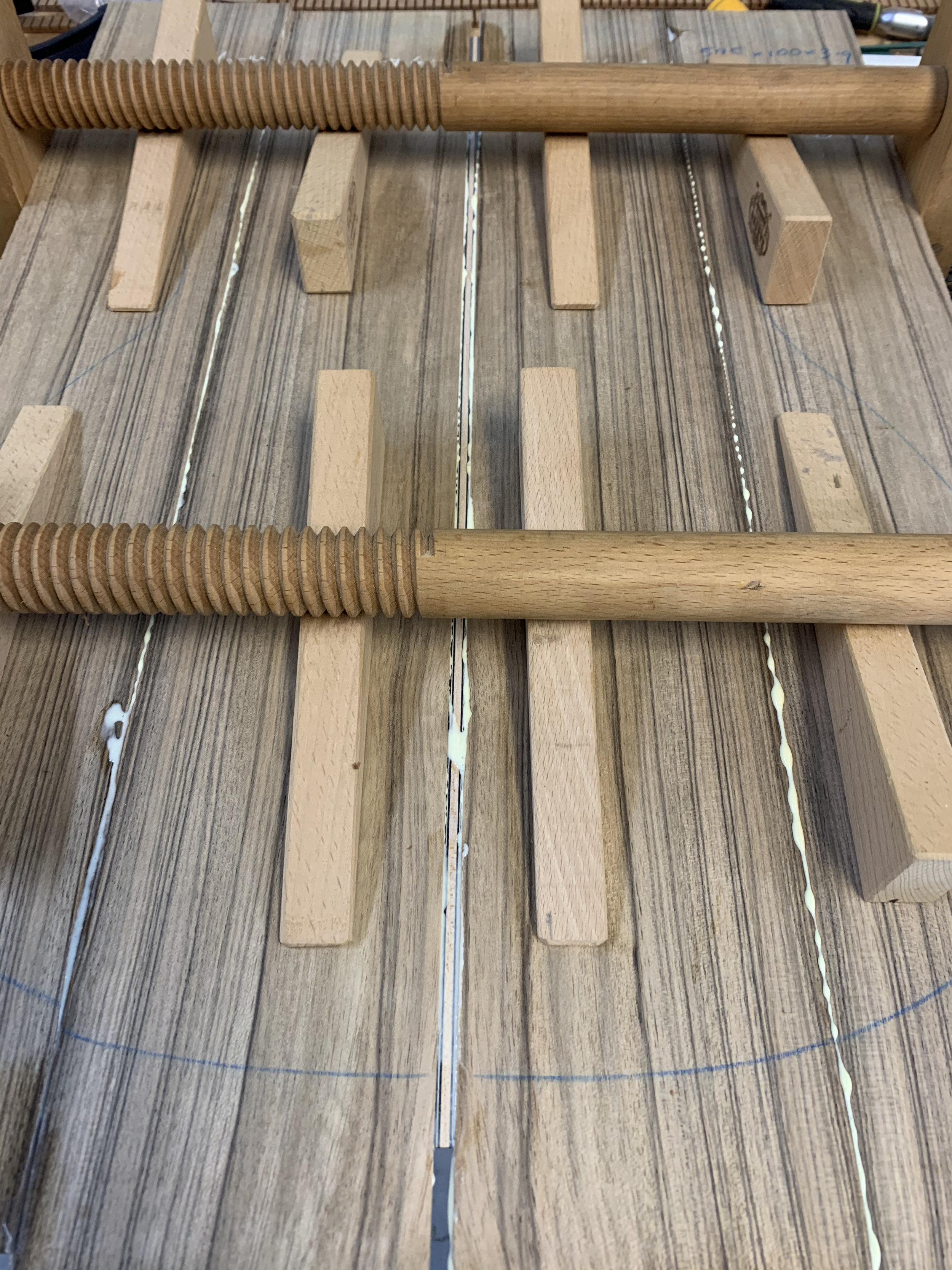 Wooden clamps holding pieces of wood being glued together