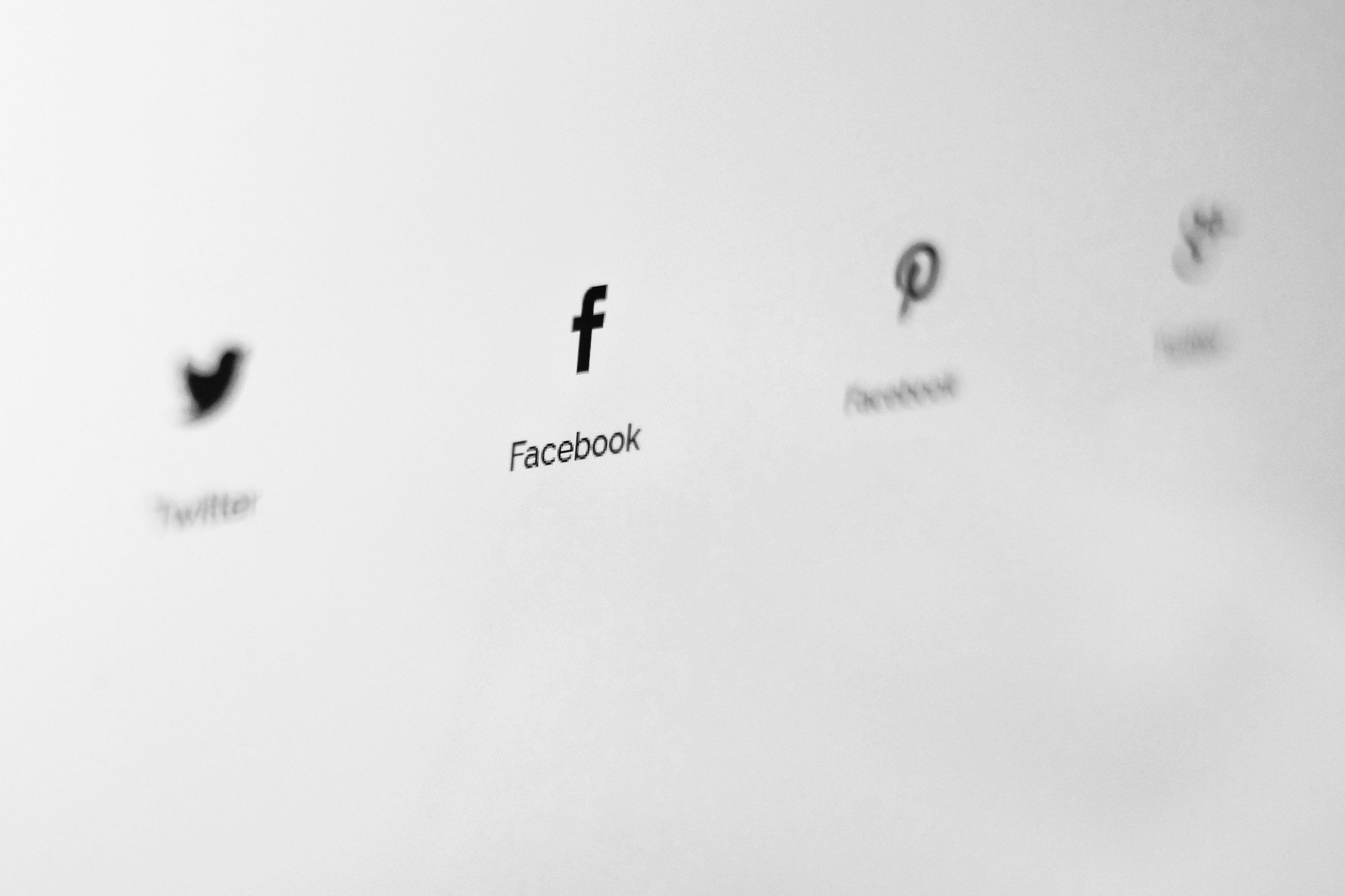 Black and white image of social media icons including Twitter, Facebook, Pinterest, and Instagram on a screen.