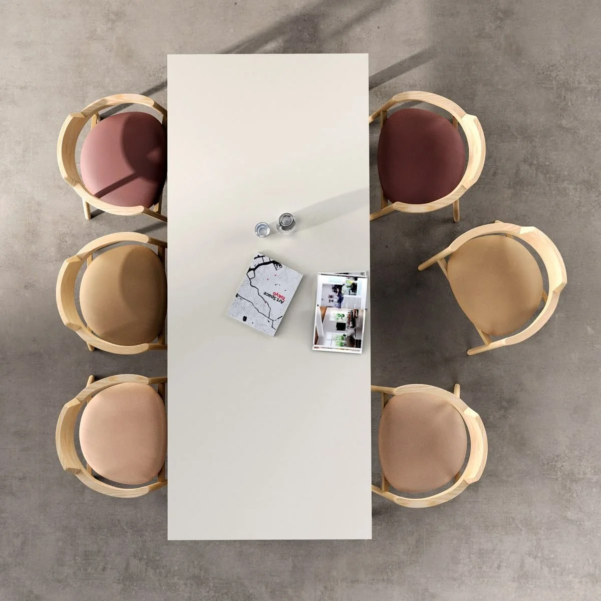 Top-down view of a white conference table with six wooden chairs around it, two on each long side and one at each end, on a gray concrete floor. Items on the table include two salt and pepper shakers, a map, and a brochure with interior photos.