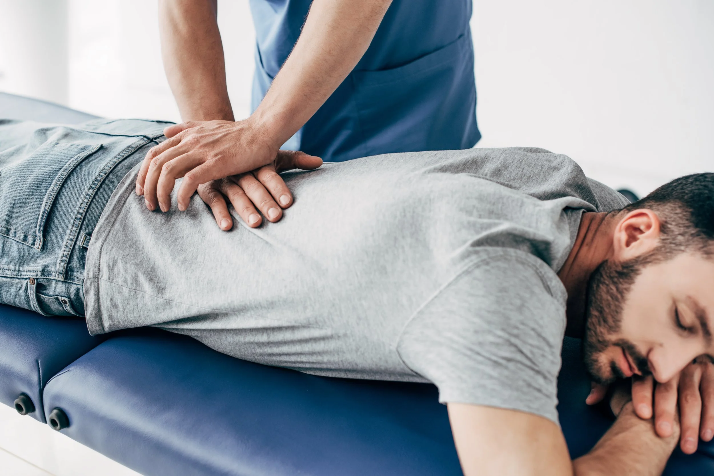 A person receiving a lumbar spine recoil adjustment during a chiropractic visit.