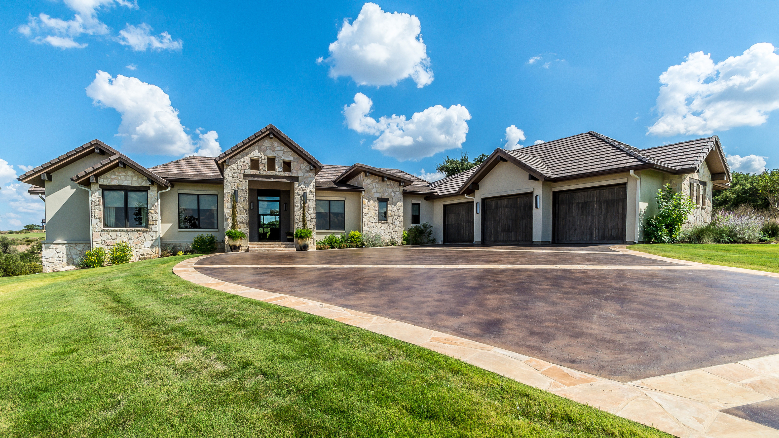 Colored concrete driveway in residential home with warm tone finish and clean edges