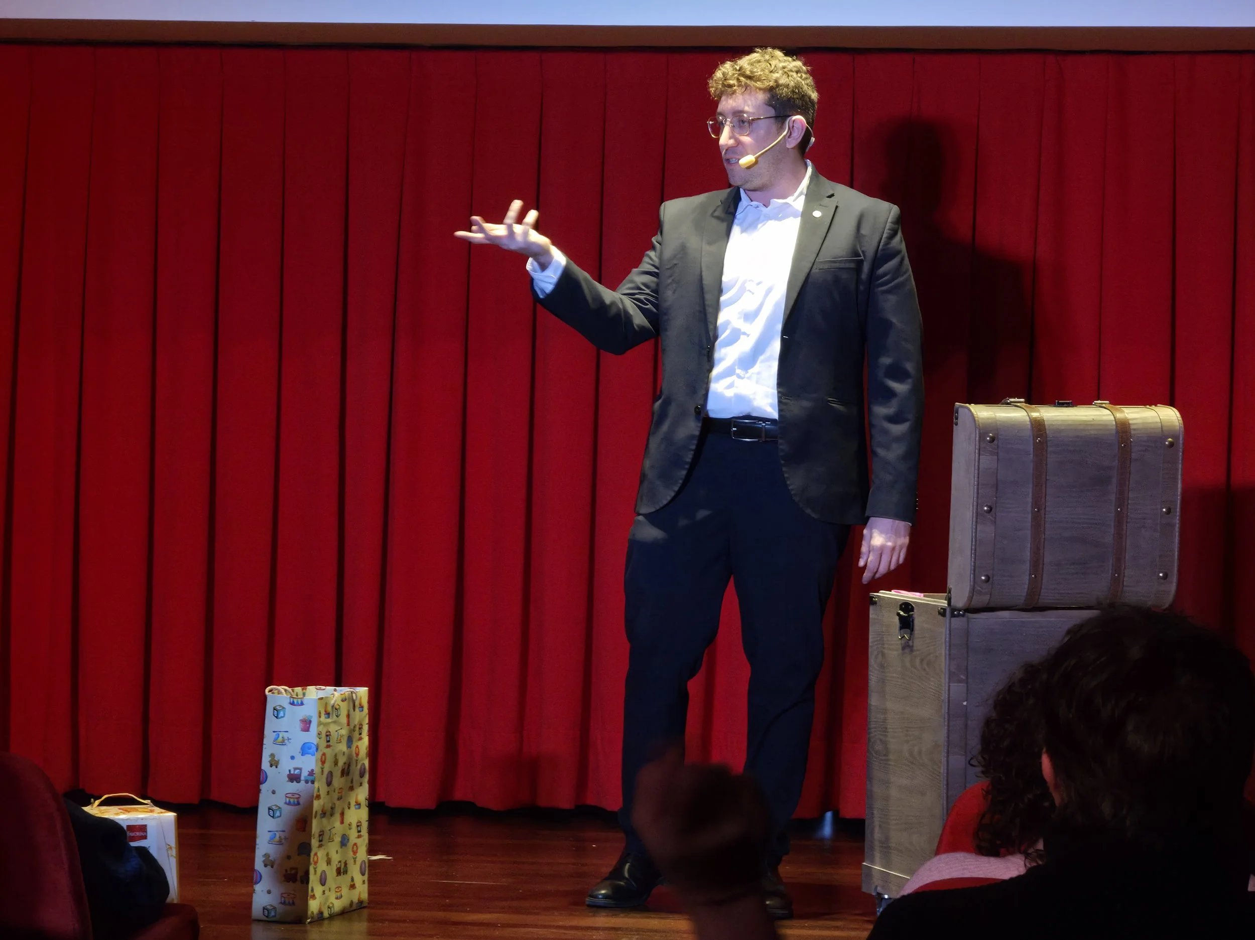 Mago Cofano mago comico e illusionista cabarettistico durante uno spettacolo teatrale dal vivo, con interazione ironica e stile da cabaret