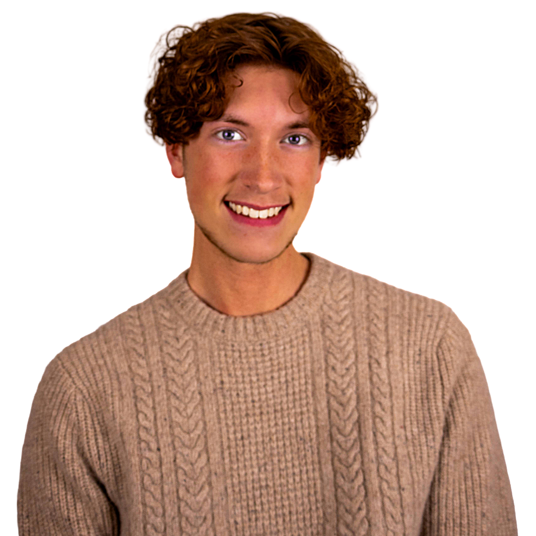 A young man with curly red hair, wearing a beige knit sweater, smiling at the camera.