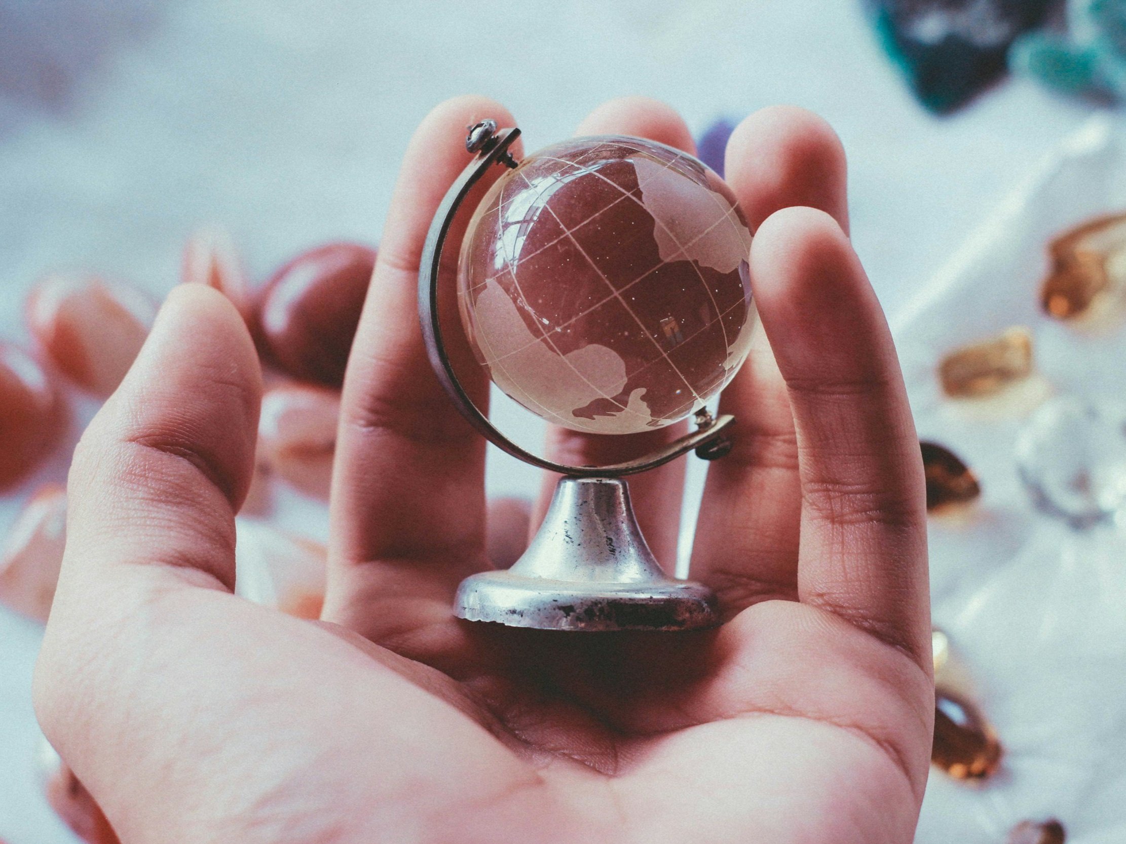 A small globe with a stand being held in a person's hand.