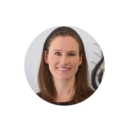 Smiling woman with long brown hair and a black headband, facing camera against a plain background.