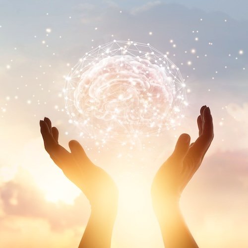 Two hands holding a glowing, digital brain icon with data points against a sunset sky.