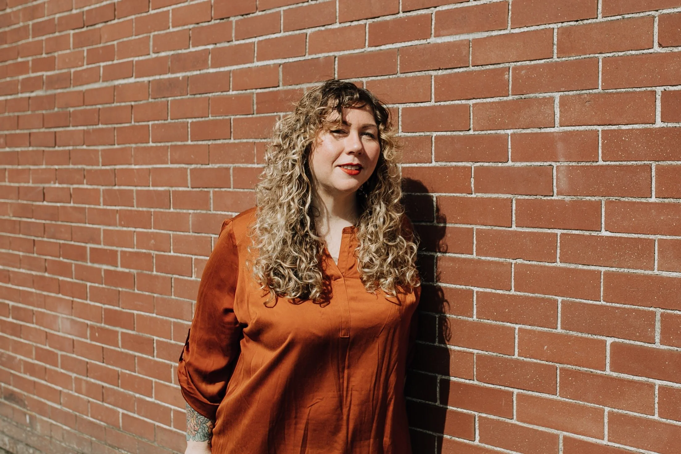 femme person looking up and smiling with long blonde curly hair