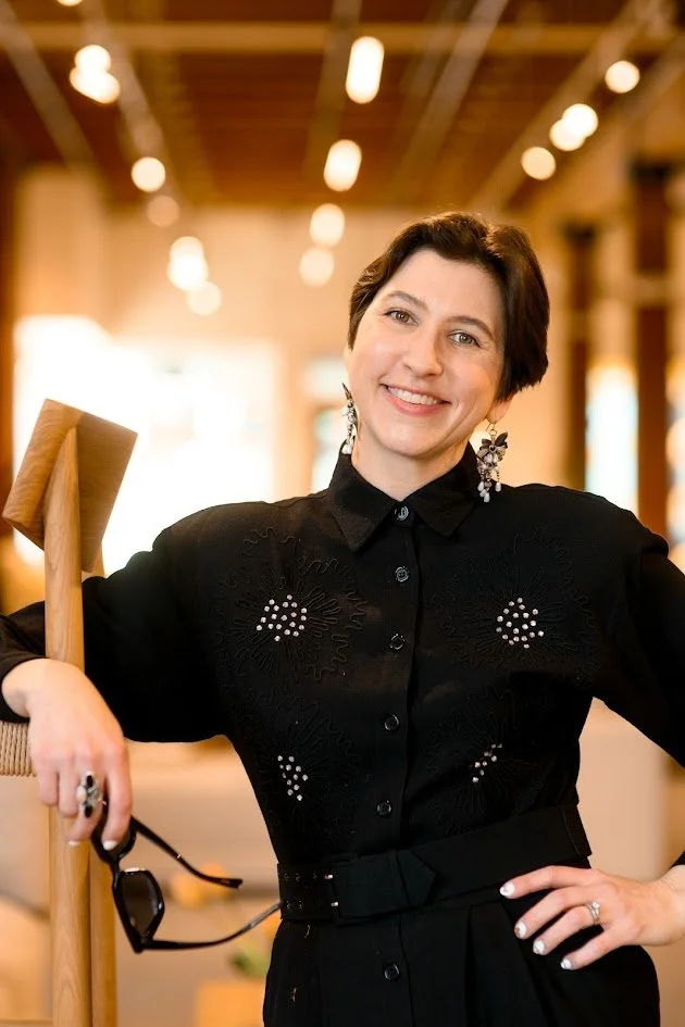 femme person with short dark hair smiling with black embellished button up shirt on