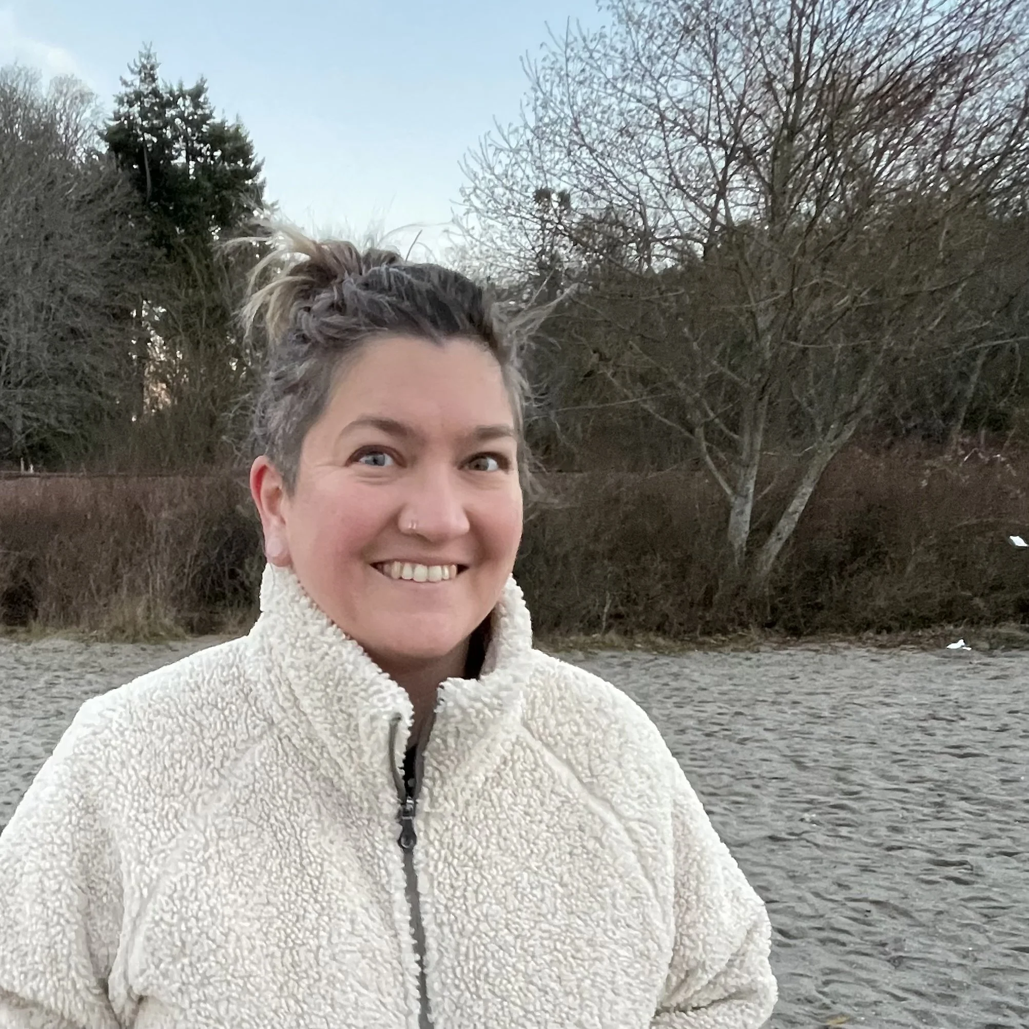 femme person smiling with hair up in white fluffy jacket