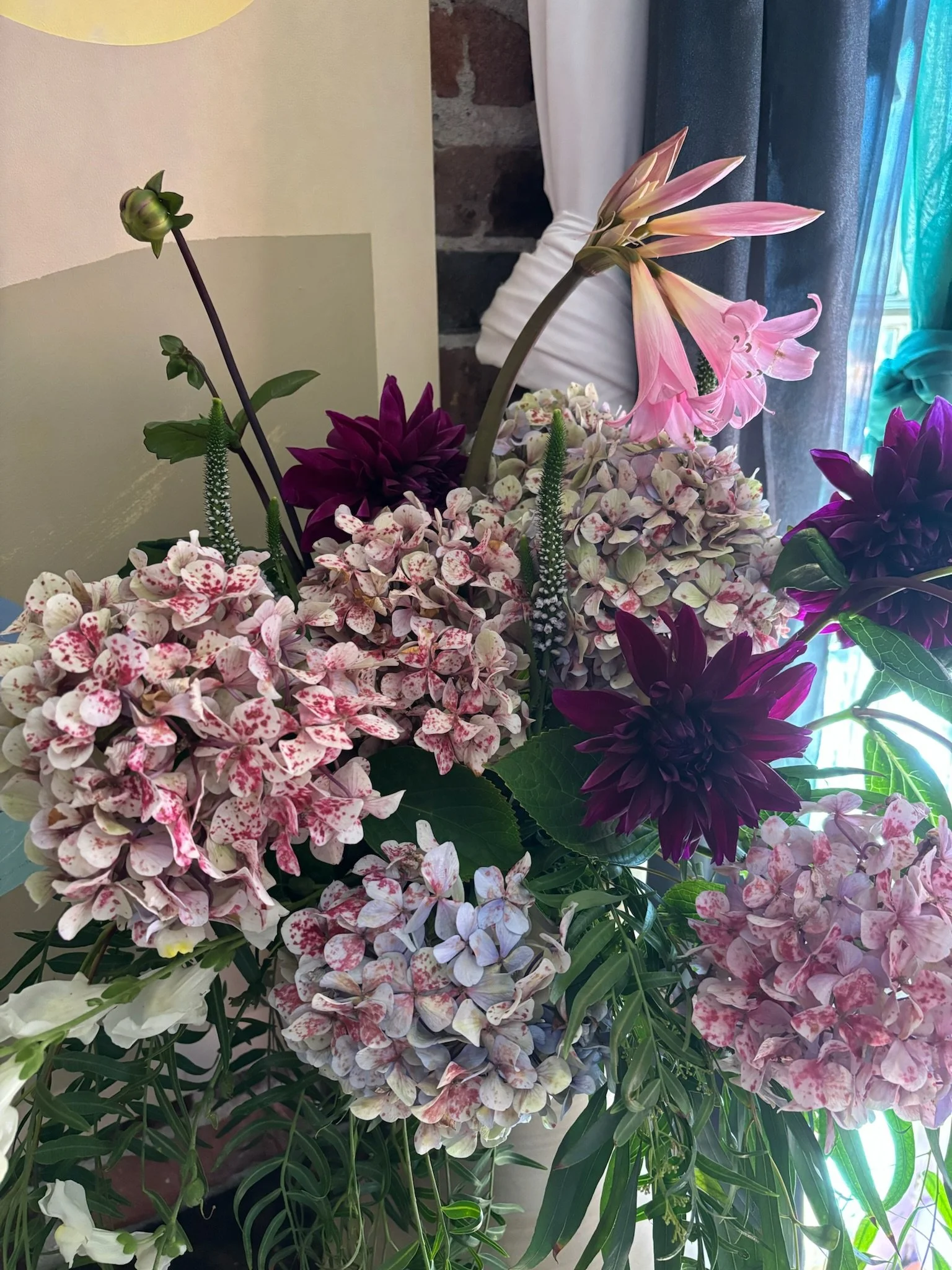 Close-up of a colorful flower arrangement with pink and purple hydrangeas, a pink lily, and other greenery.