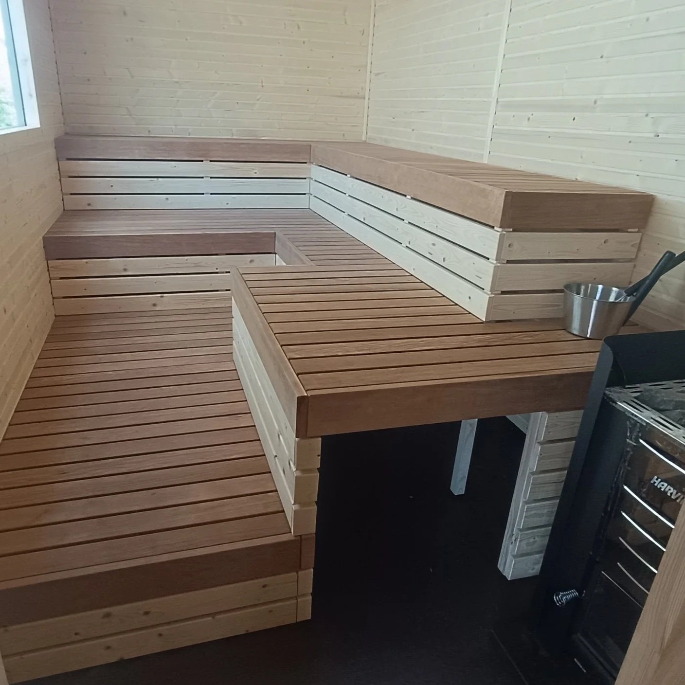Interior of a wooden sauna with tiered seating and a small window.