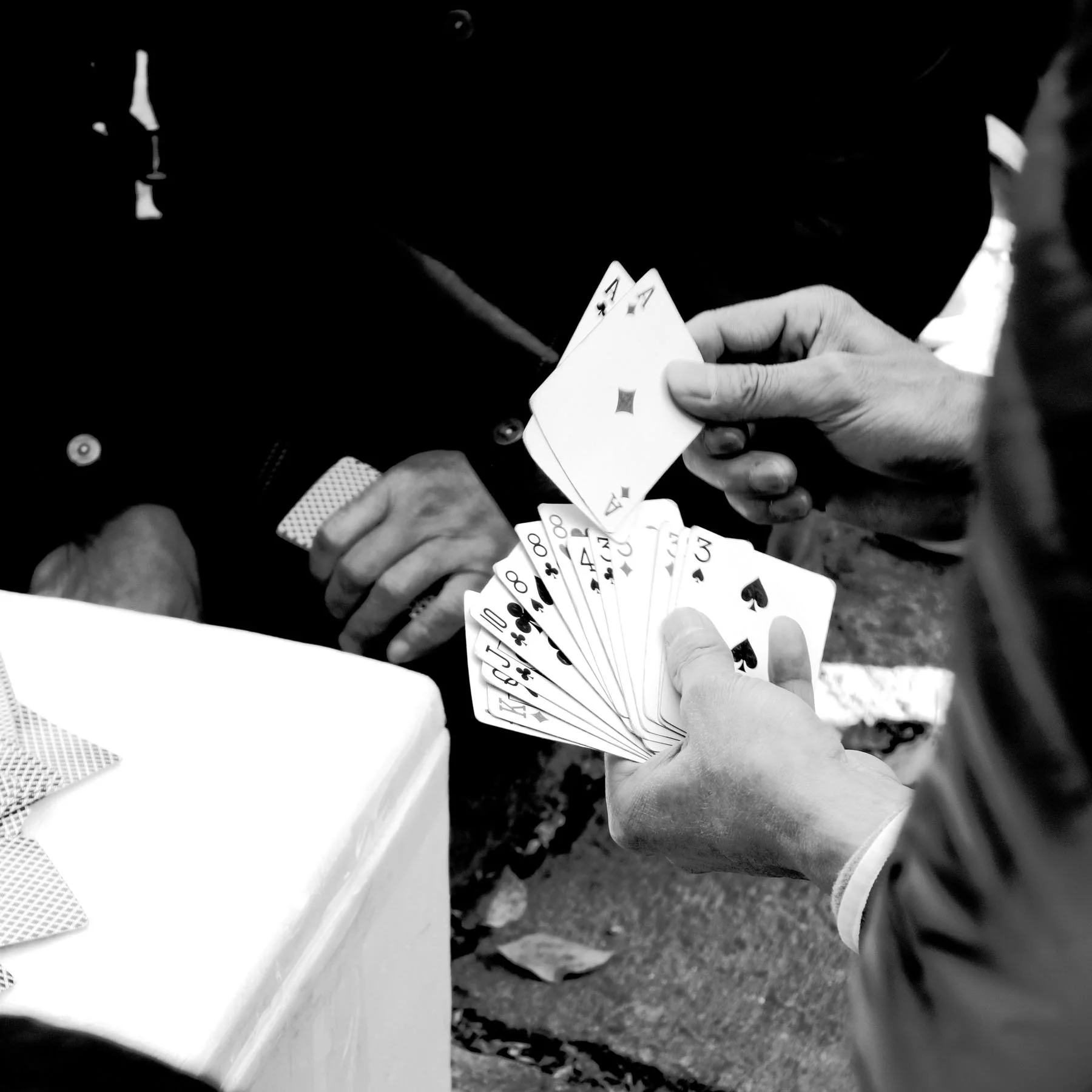 Someone playing a card game, holding a fan of playing cards with a pair of aces visible, in black and white.