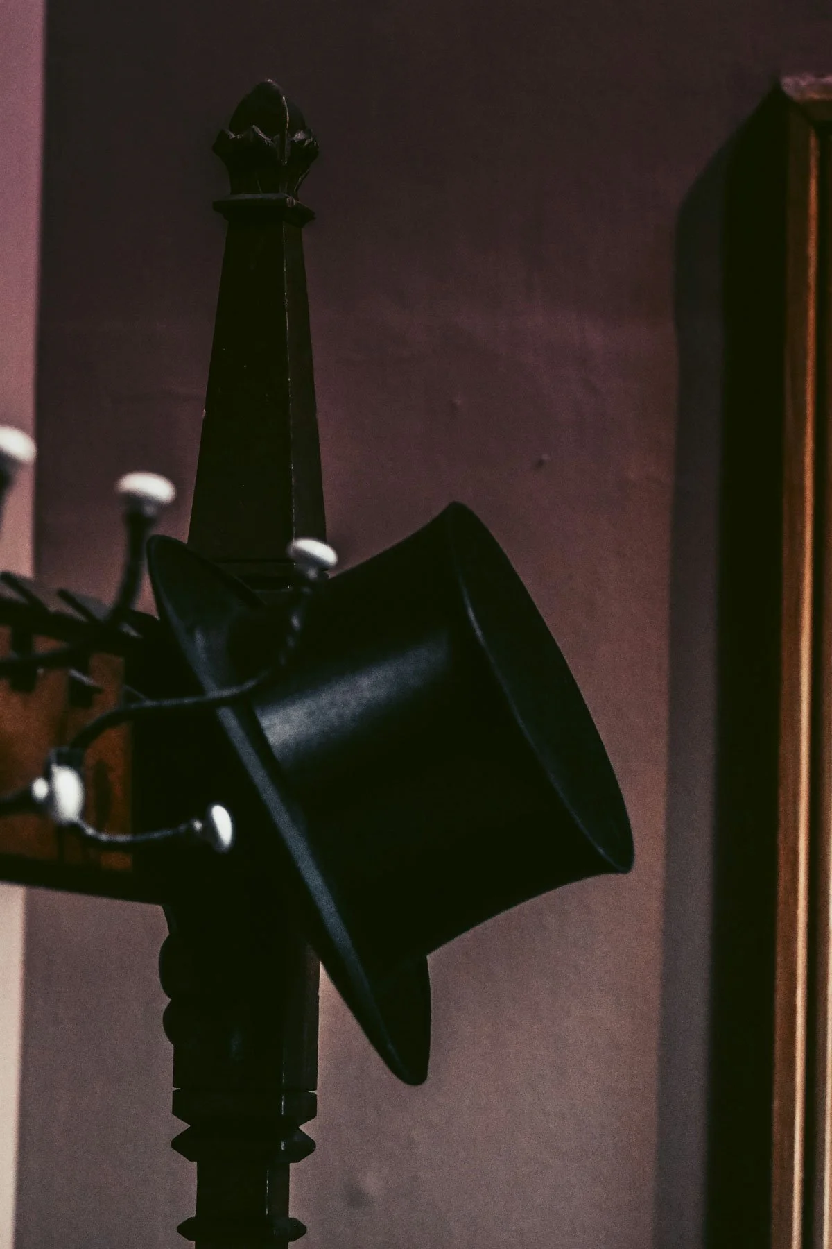 A microphone with a pop filter in a recording studio, with a decorative black ice scraper sitting on top of a stand in the background, against a dark wall.