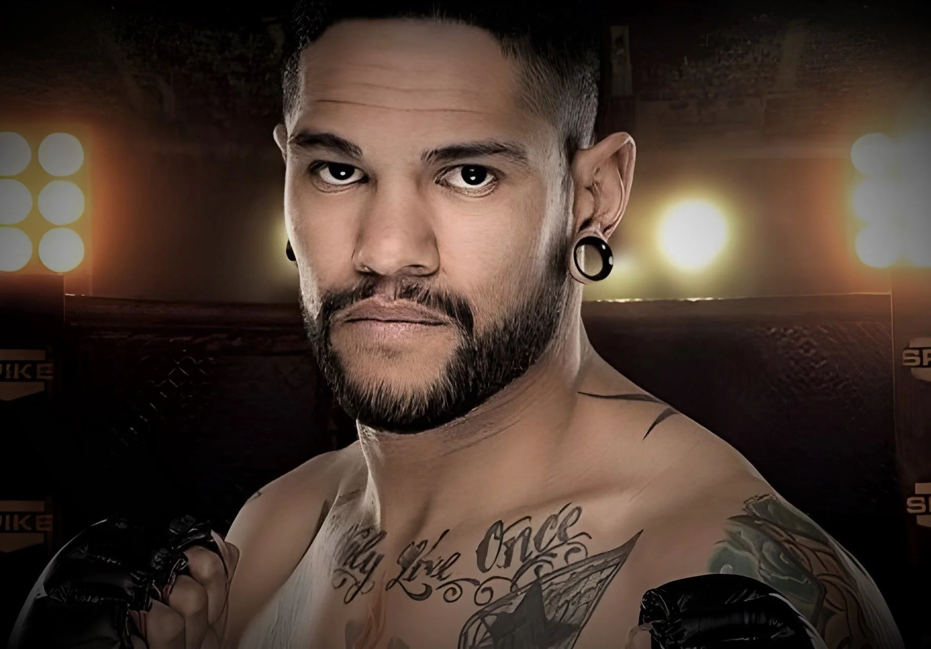 Shirtless man holding a championship belt, standing against a brown background.