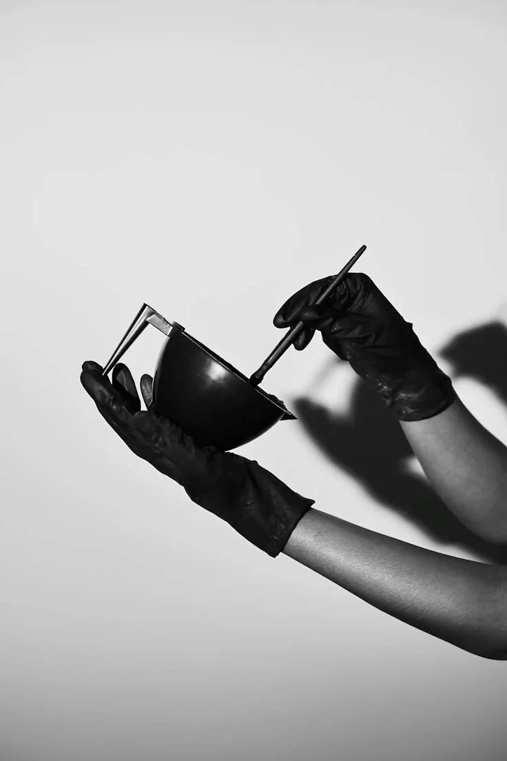 Black and white photo of a person with hair wrapped in foil, possibly undergoing hair coloring treatment.